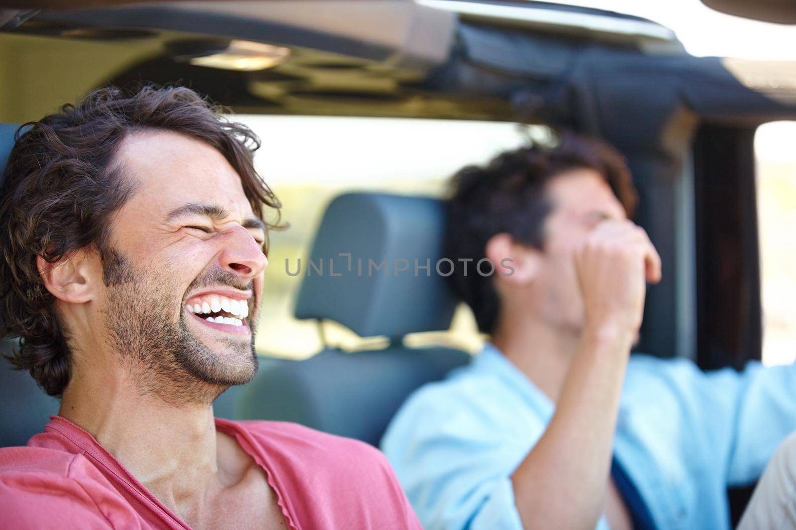 Two friends happy and laughing together while on a drive.