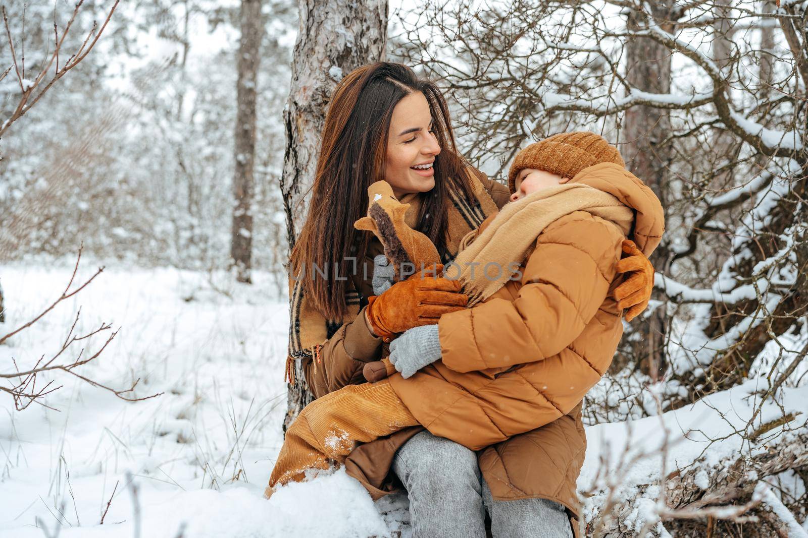 Woman with a little son on a winter hike in the snowy forest by Fabrikasimf