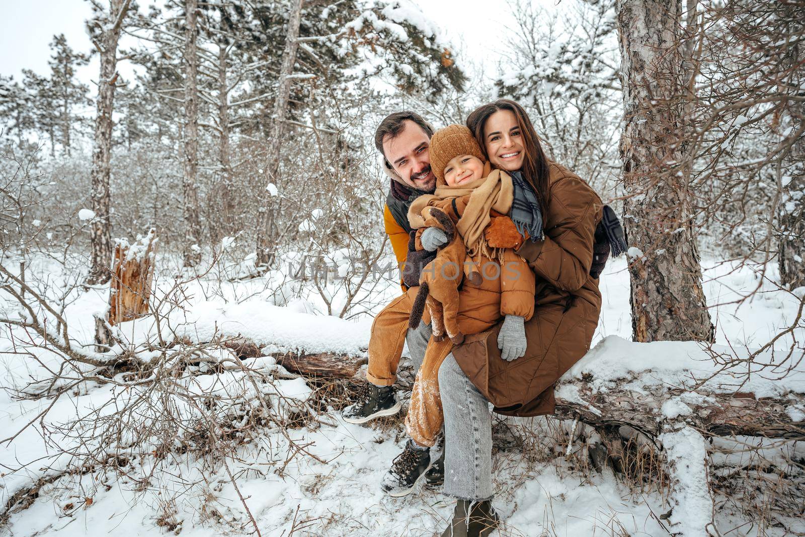 Portrait of happy family in winter clothes in forest by Fabrikasimf