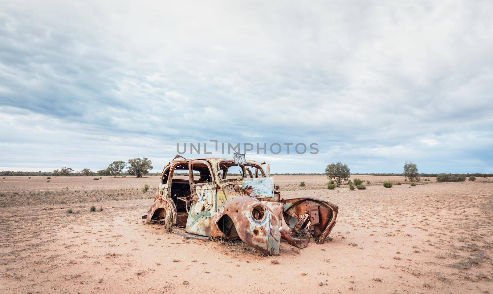 Rusting old car sits in barren dusty earth in outback Australia