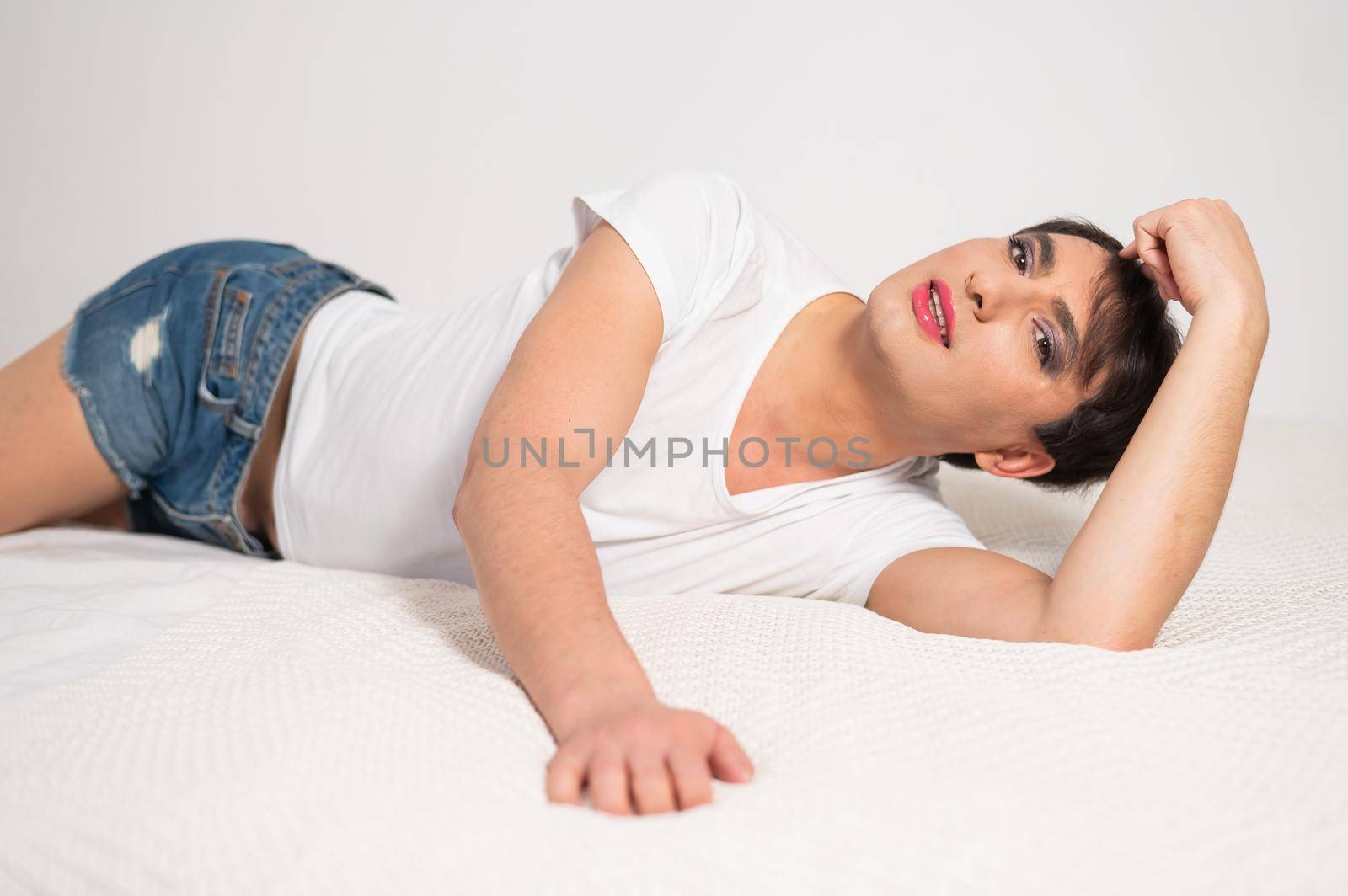 Caucasian transgender man lies on gay bed. Outdoor gay posing in the bedroom. by mrwed54