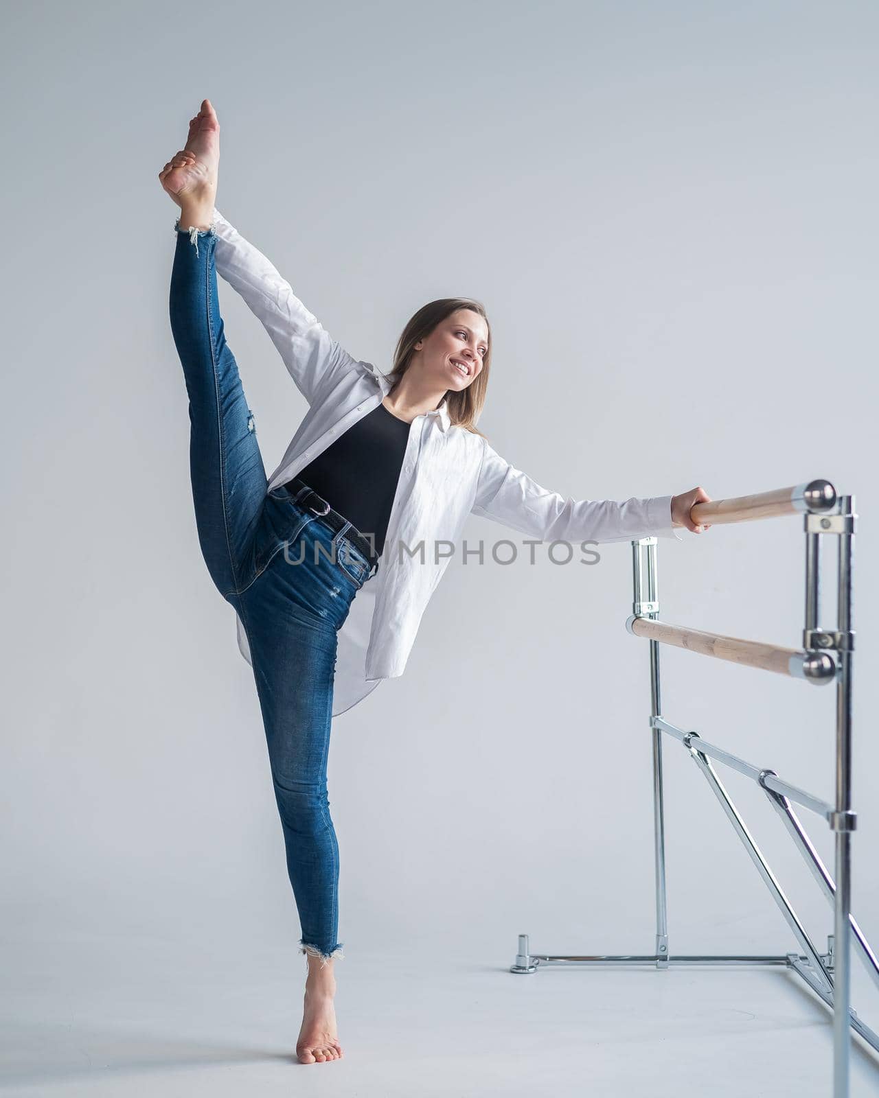 Caucasian woman in casual clothes pulls the longitudinal split at the ballet barre. by mrwed54
