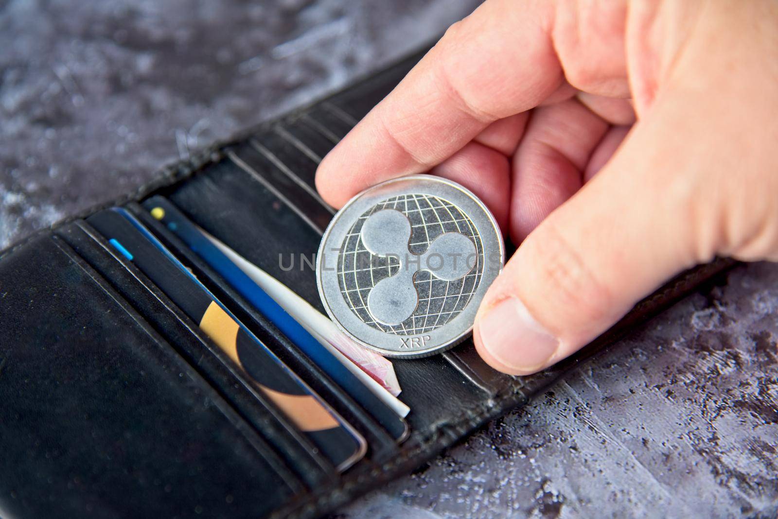 Crypto coin, XRP Ripple coin in leather wallet on concrete style background with clipping path. Hand holding a Coin. Cryptocurrency business concept. High quality photo