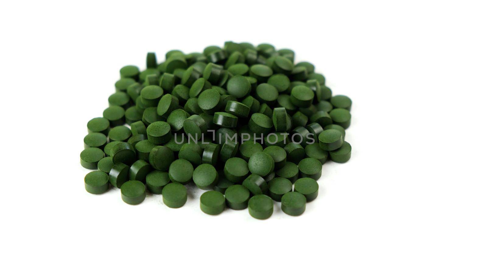Spirulina algae tablets isolated on white background. Nutritional supplements, vitamins and health concept.