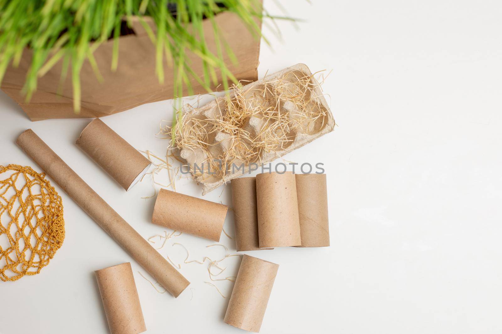 Household waste rollers from cardboard and paper lie on a white table, a knitted bag. The concept of recycling and environmental protection. Top view