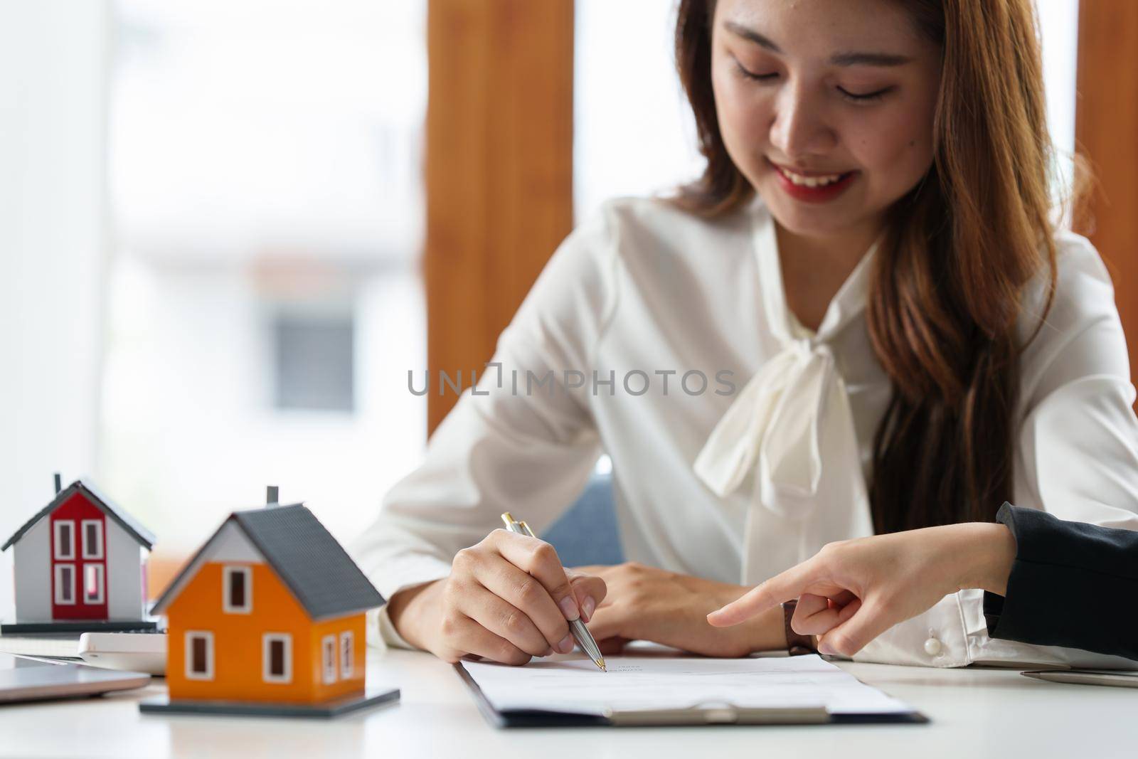 Close up of Business woman pointing and signing agreement for buying house. Bank manager concept