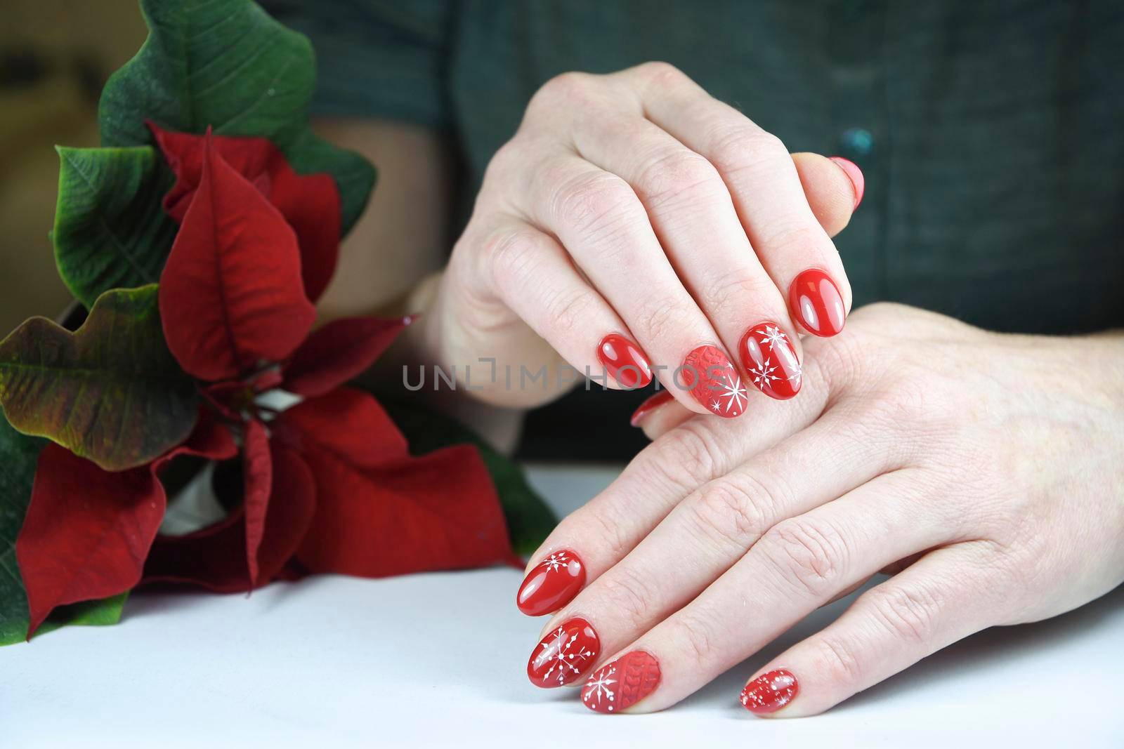 female hands with beautiful red holiday manicure design holding mini poinsettia flower, christmas decor for beauty, High quality photo