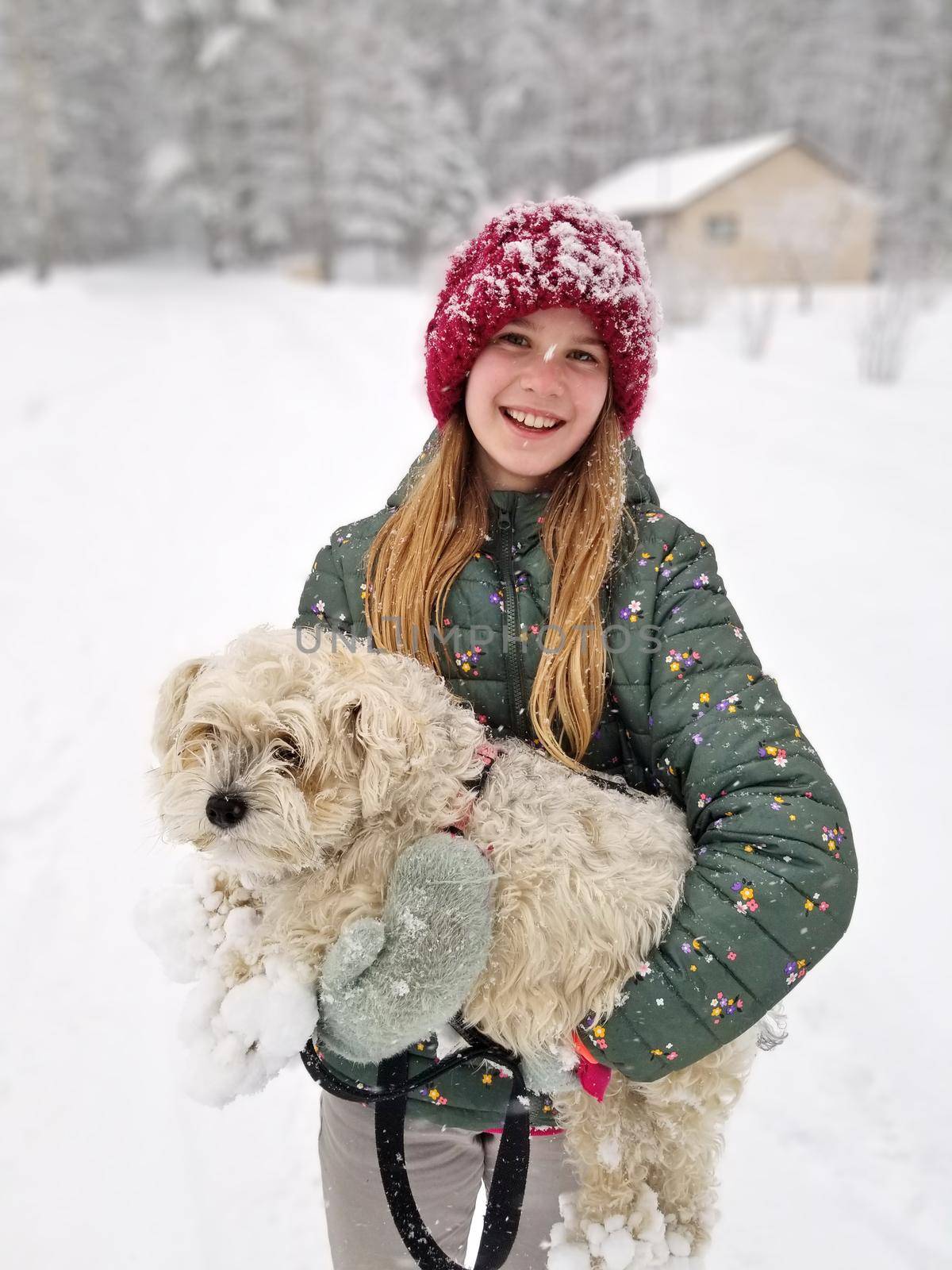Portrait of A Smiling young girl holding up her Extremely Shaggy Dog Whose Paws are Caked in Snow. High quality photo