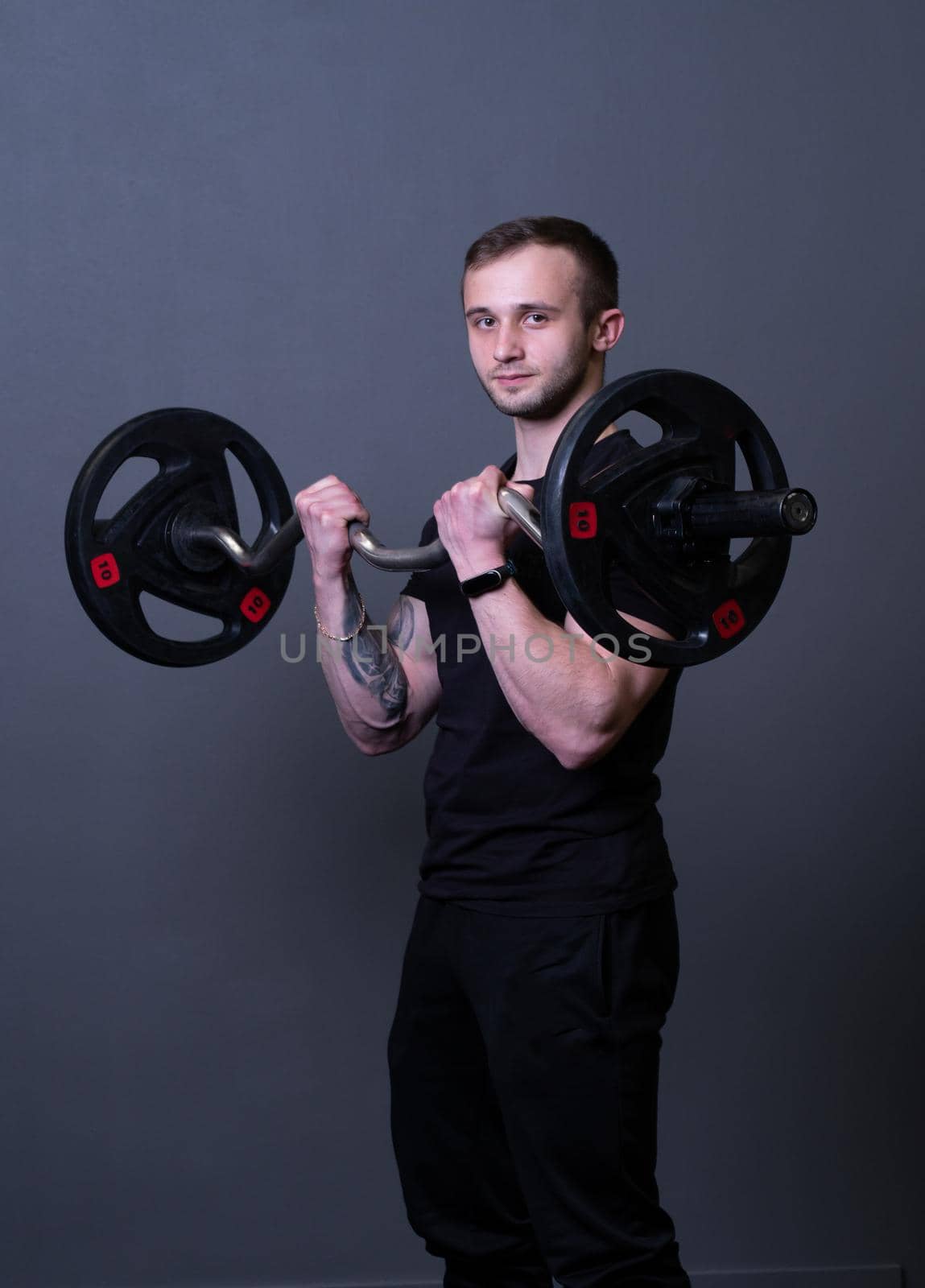 Guy with a barbell in a black fitness T-shirt muscular bodybuilder barbell fit, for strong active in workout for handsome athletic, biceps triceps. Lifting young bar, practicing arm