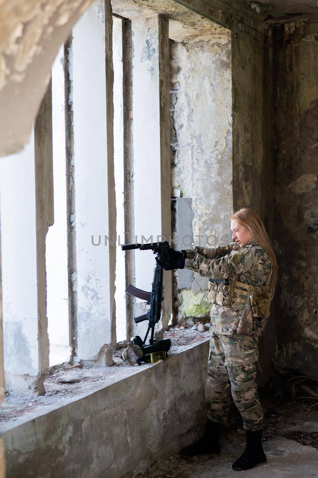 A woman in an army uniform aims to shoot a firearm in an abandoned building