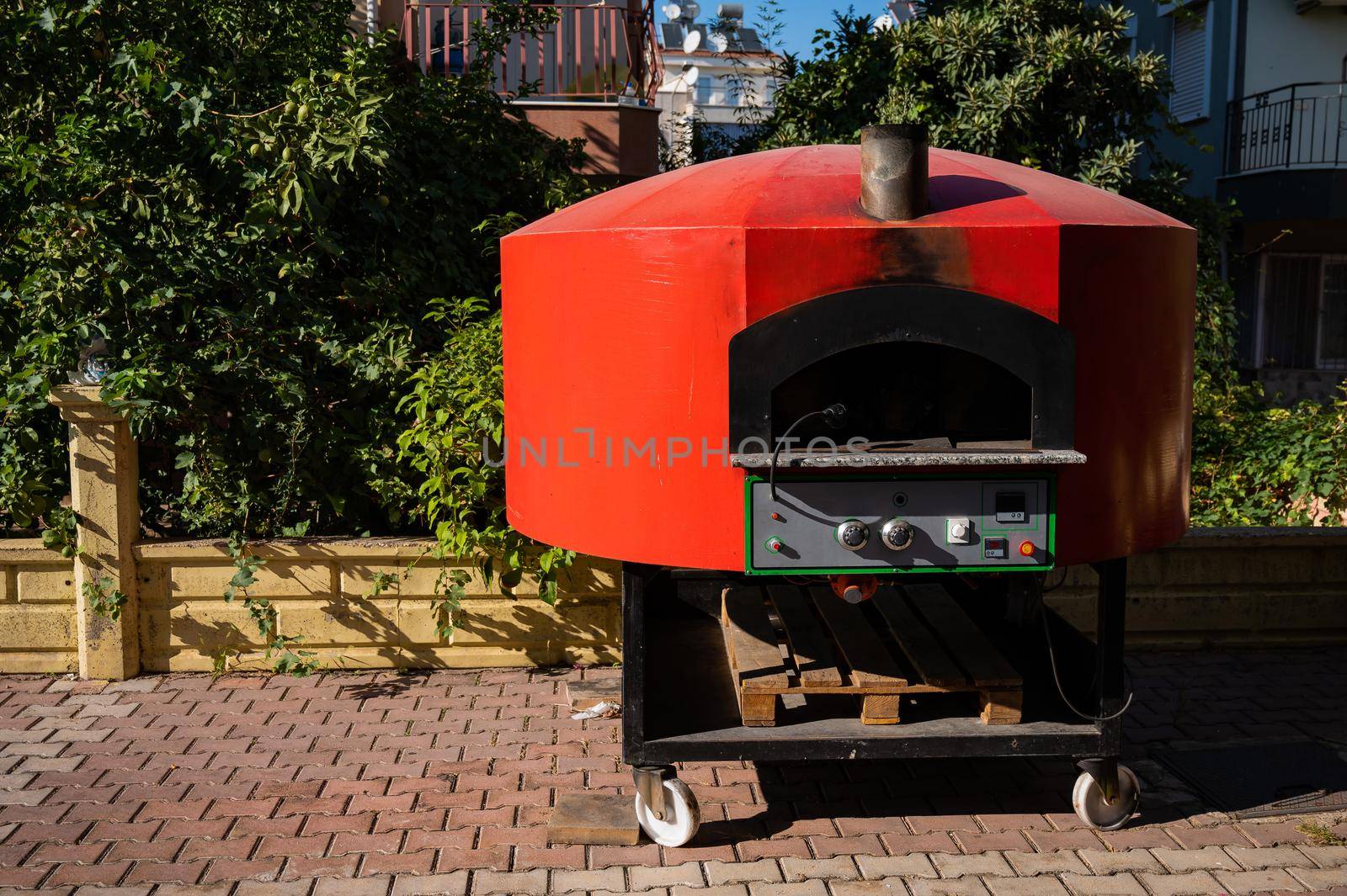 Large domed red metal outdoor pizza oven