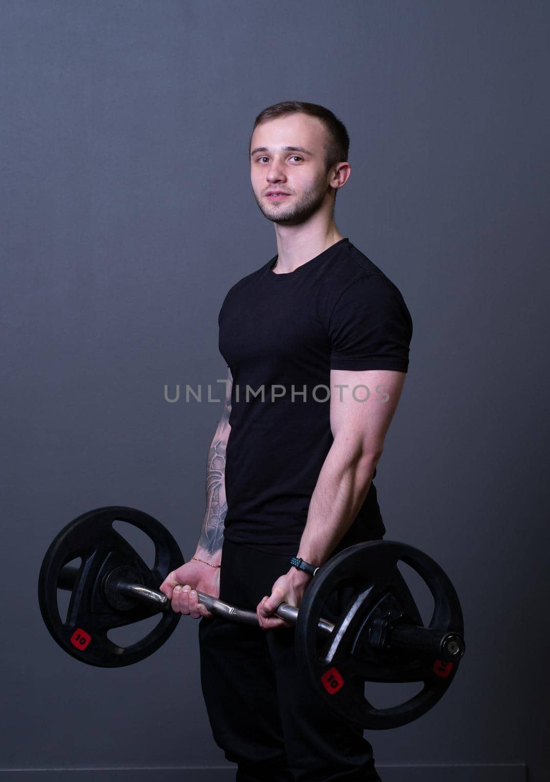 Guy with a barbell in a black fitness T-shirt muscular bodybuilder attractive fit, In the afternoon strength athlete in sport for healthy weightlifting, caucasian triceps. Man young motivation, equipment arm