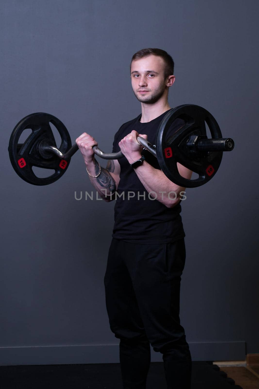 Guy with a barbell in a black fitness T-shirt muscular bodybuilder barbell fit, from strength active for workout and physical athletic, diet portrait. Lifting torso work, practicing arm