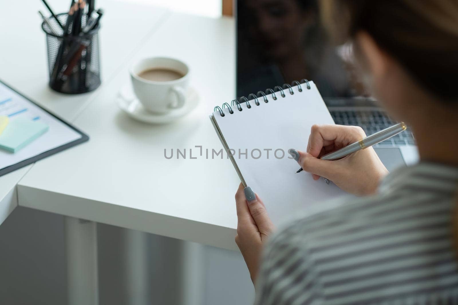 Business asian hand holding pencil and writing note on wood table,Checklist Notice Remember Planning Concept.