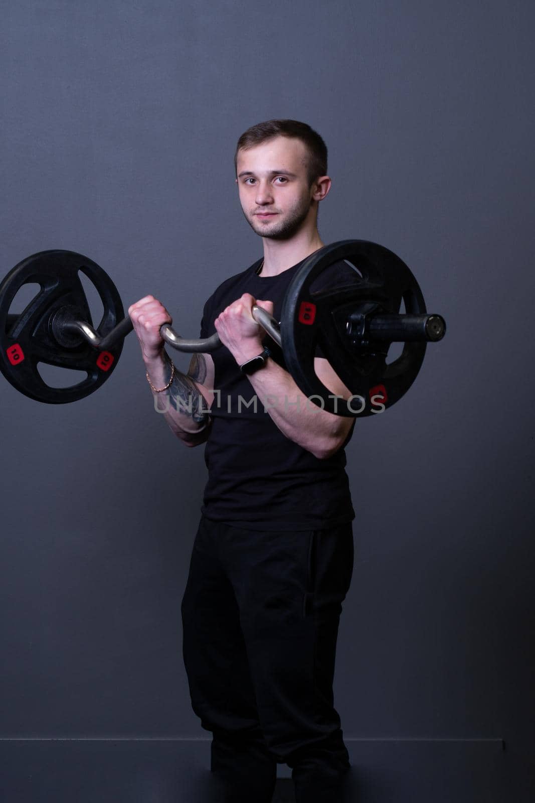 Guy with a barbell in a black fitness T-shirt muscular bodybuilder barbell bodybuilding, for strong training in gym for handsome body, background deadlift. Man young bar, health arm