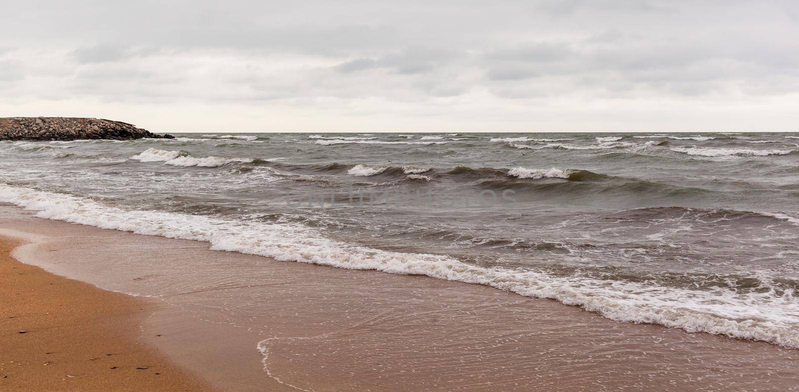 Huge waves raging in the sea and seagulls in the spray of waves. Storm at sea. Birds fly over the waves. Nature, environment, rough weather, danger