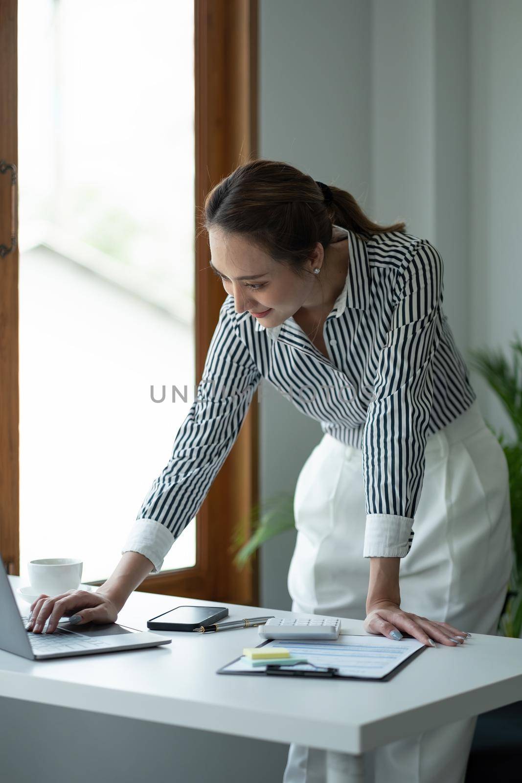Portrait Female Entrepreneur. Cheerful asian Businesswoman standing and using laptop computer