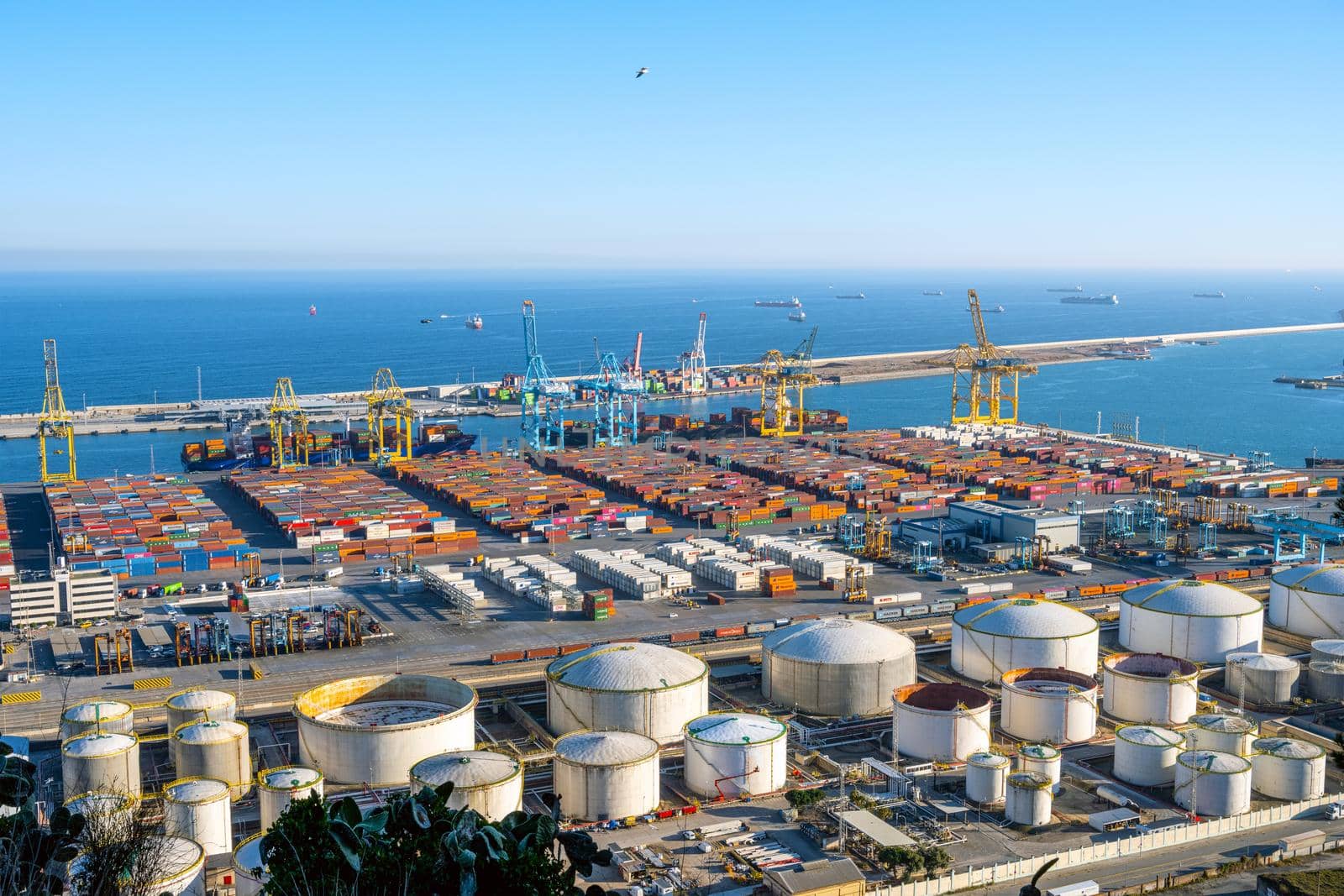 BARCELONA, SPAIN - February 02, 2022: The commercial harbour of Barcelona with containers, cranes and storage tanks