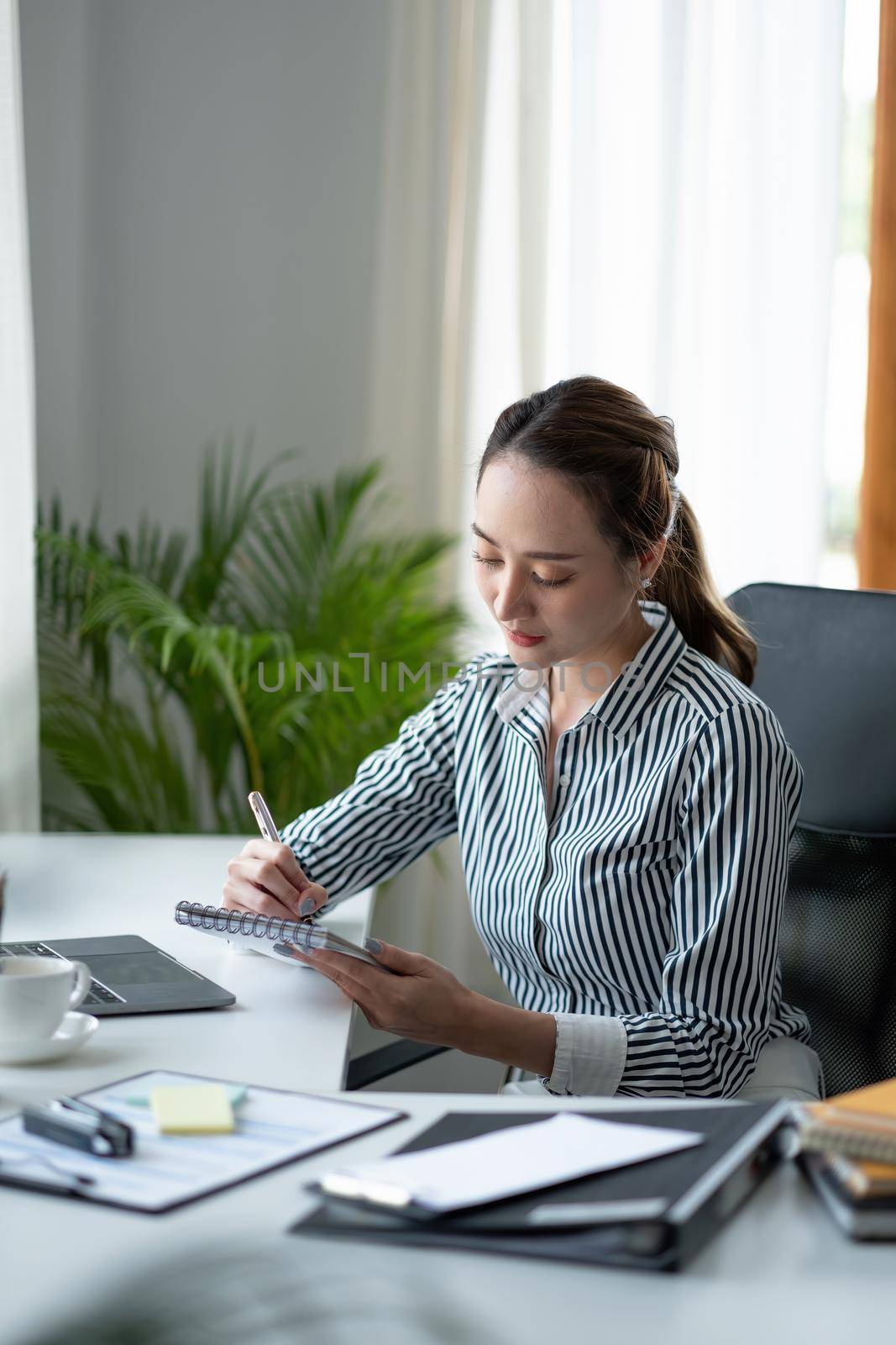 Business asian hand holding pencil and writing note on wood table,Checklist Notice Remember Planning Concept.