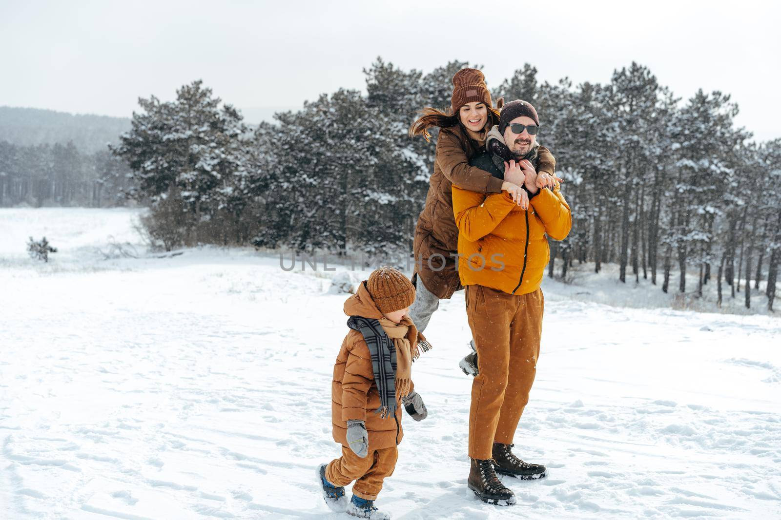 Happy family having a walk in winter outdoors in snow forest