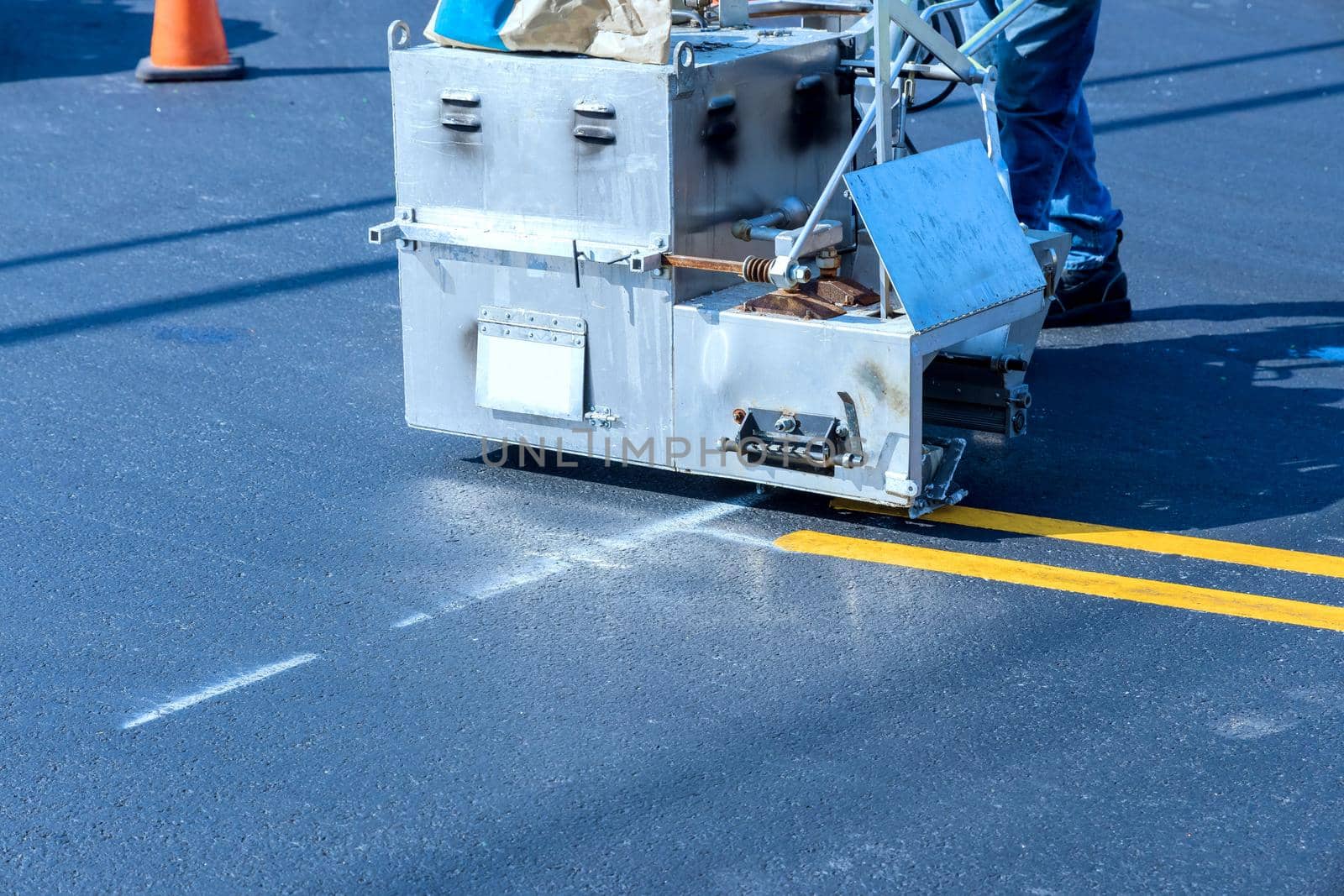 Road workers use hot-melt scribing machines to painting line on asphalt road surface in the city