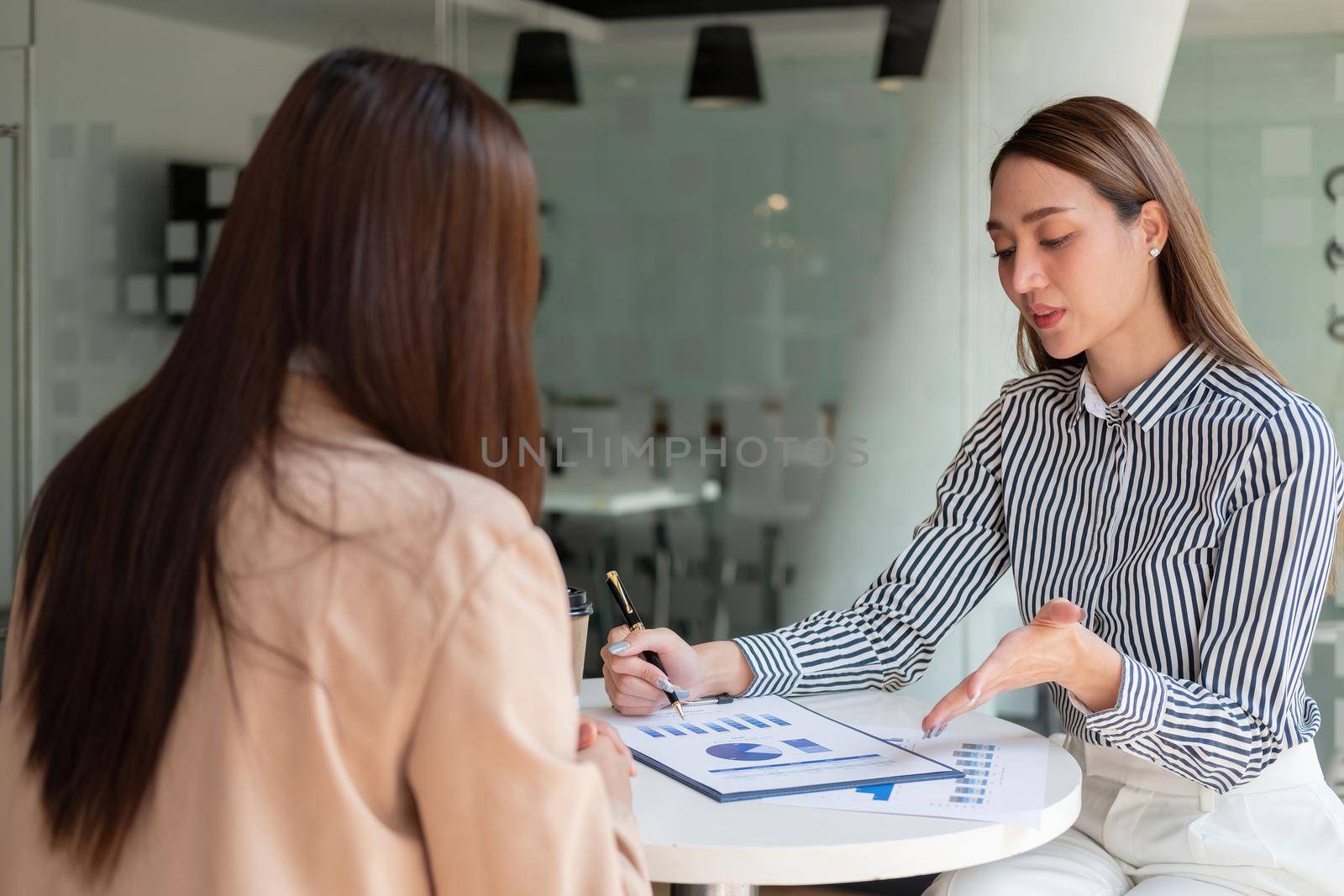 Two asian business woman colleagues meeting to conference professional investor working and discussing a new marketing business strategy project, Business finance and accounting concept.