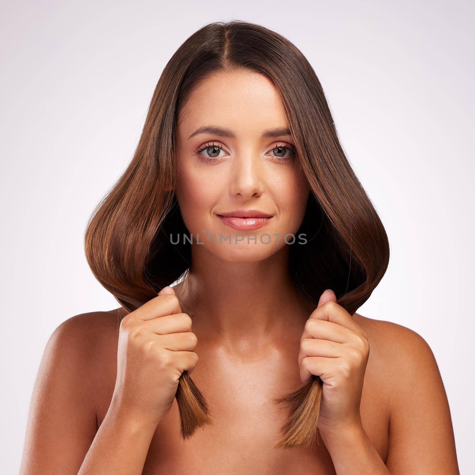 No split ends here. Studio portrait of an attractive young woman posing against a grey background. by YuriArcurs