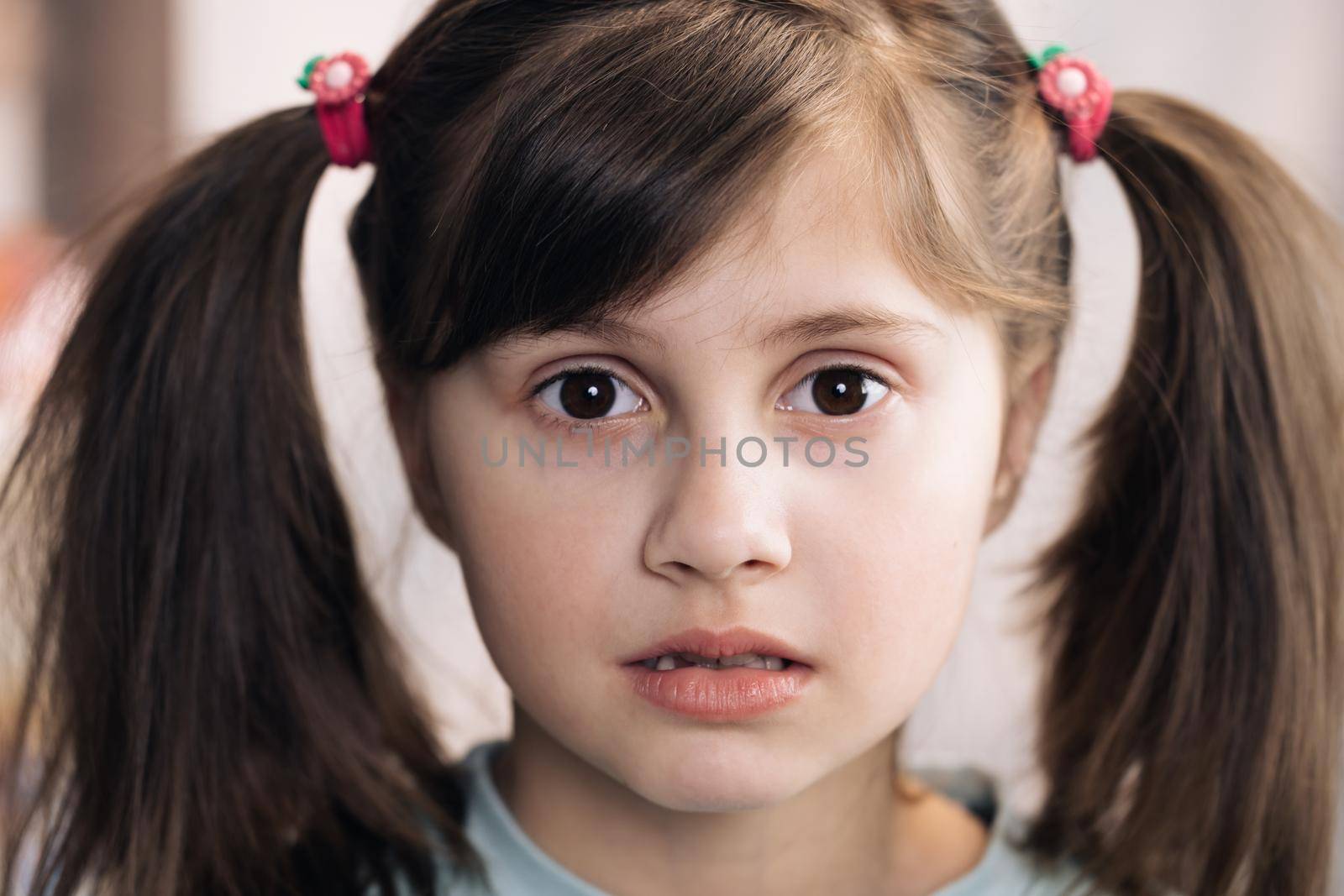 Close-up portrait of caucasian black haired girl isolated home. Emotional child. Adorable child with big brown eyes surprisingly react on something, look at camera.