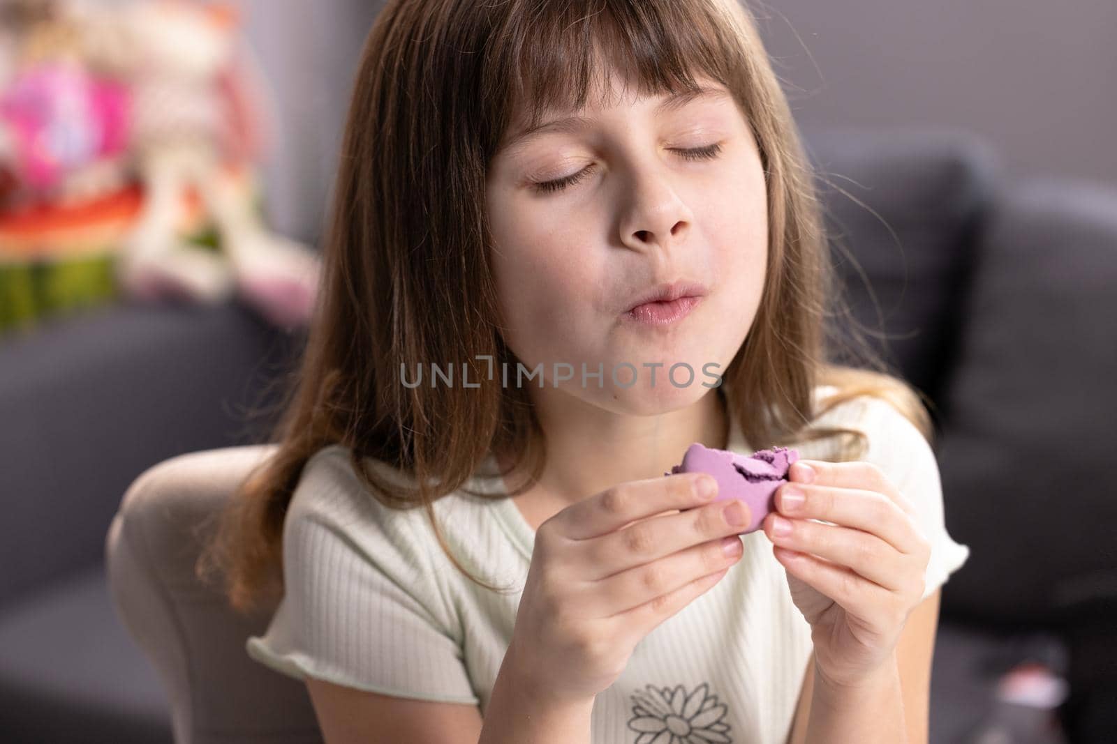 School girl on a home background, licks her lips, eating one violet macaron, closes her eyes with pleasure. Dessert person, sweet tooth, gourmet. Feeling good, delicious by uflypro