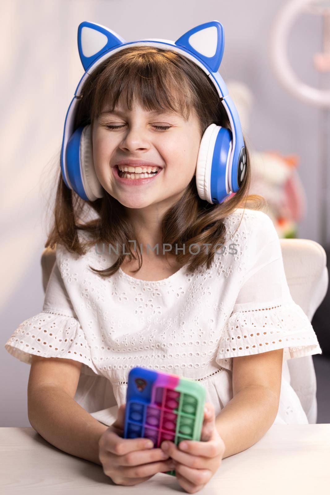 Happy hipster teen girl wear headphones listen dj pop music in the Living Room. Smiling gen z teenager model dancing