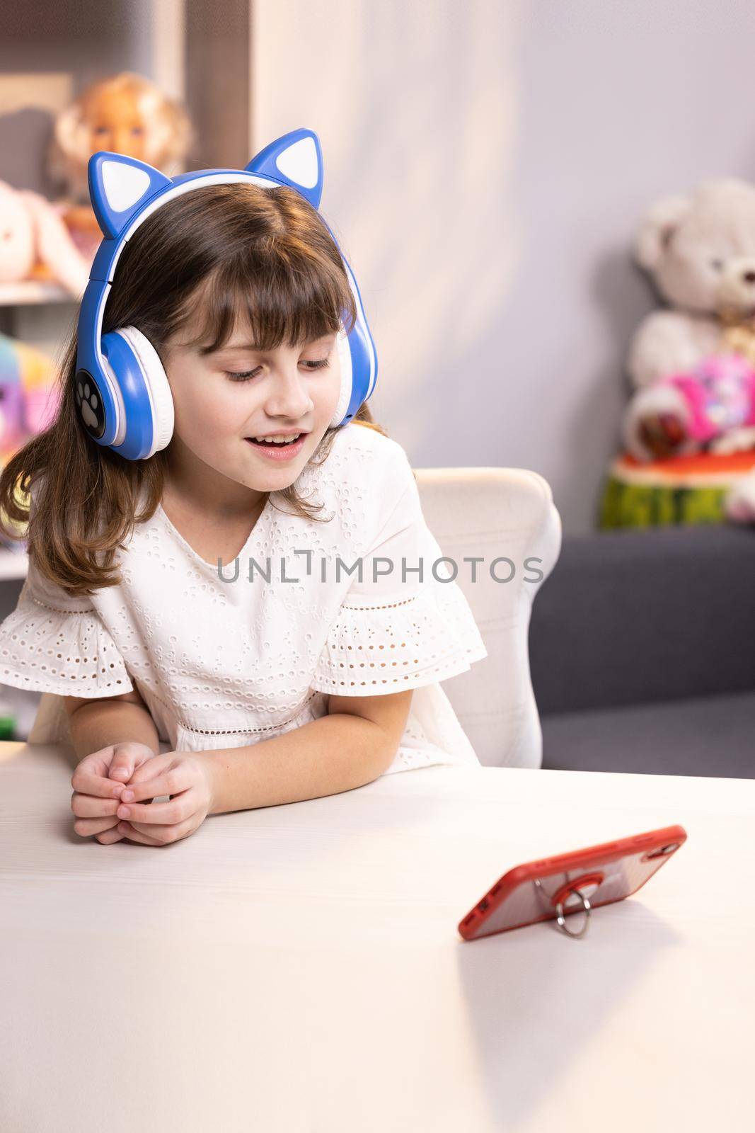 Cute small kid girl vlogger talking to camera at home recording vlog for social media blog, video conference calling virtual friend having online meeting sitting in chair by uflypro