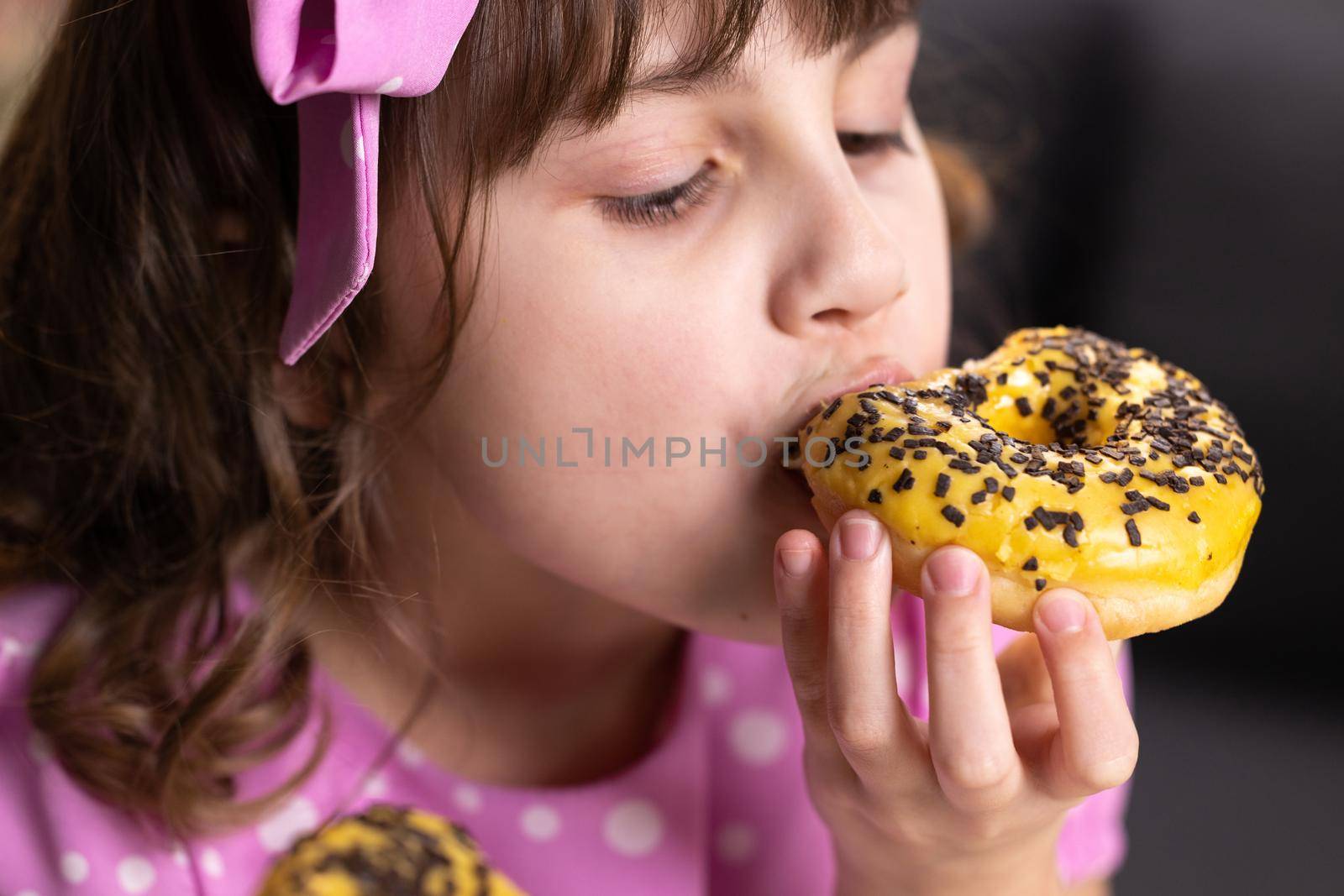 Portrait of young hungry girl eating donut. Female mouth bites a loaf. Close-up woman eating donut , delicious, sweet, sweet tooth at home background. by uflypro