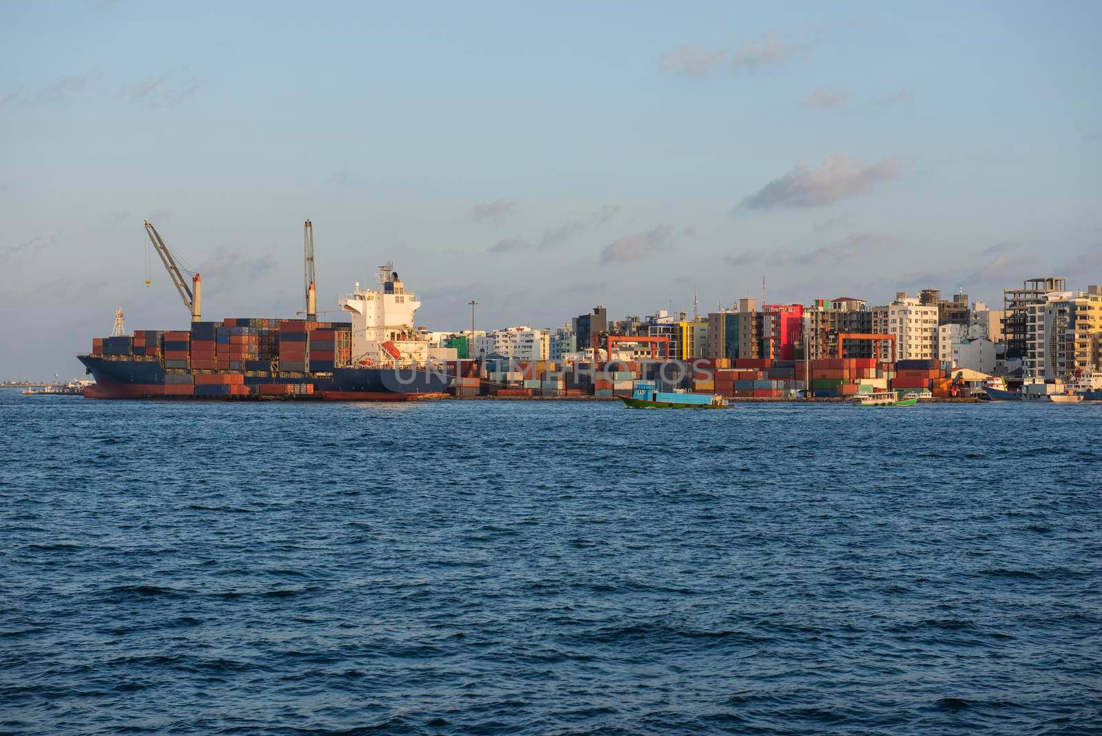 Large container ship moored in commercial industrial shipping port on island city in open ocean