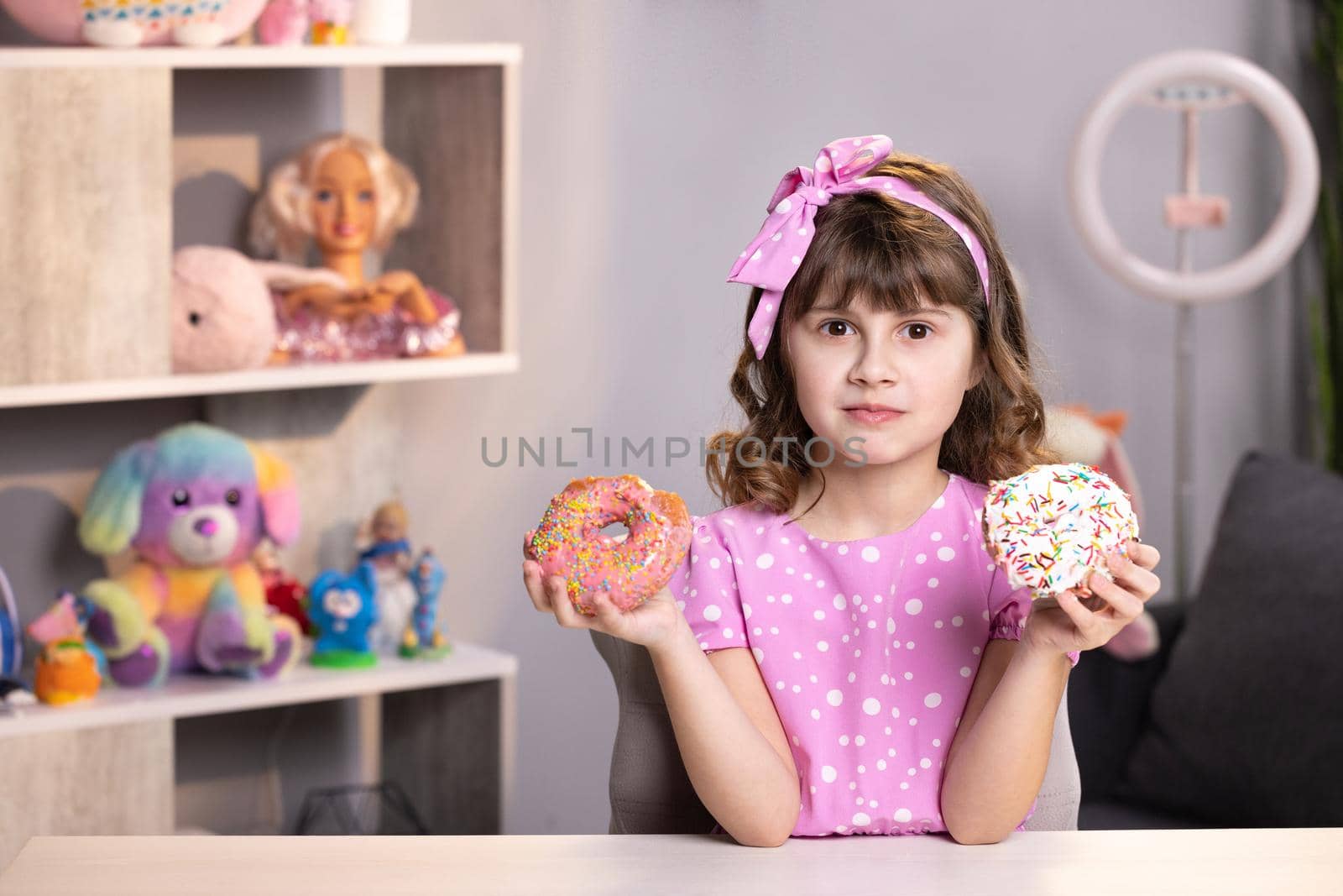 Lovely joyful school girl can not choose between a pink donut and yellow fresh macaroon. Healthy lifestyle, sweets, sweet tooth. Being on a diet by uflypro