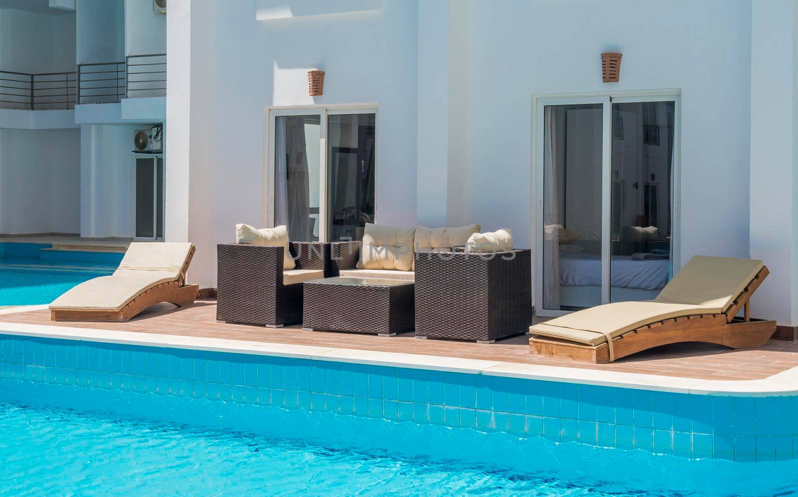 Outdoor terrace patio furniture at a luxury holiday apartment in tropical resort with swimming pool view