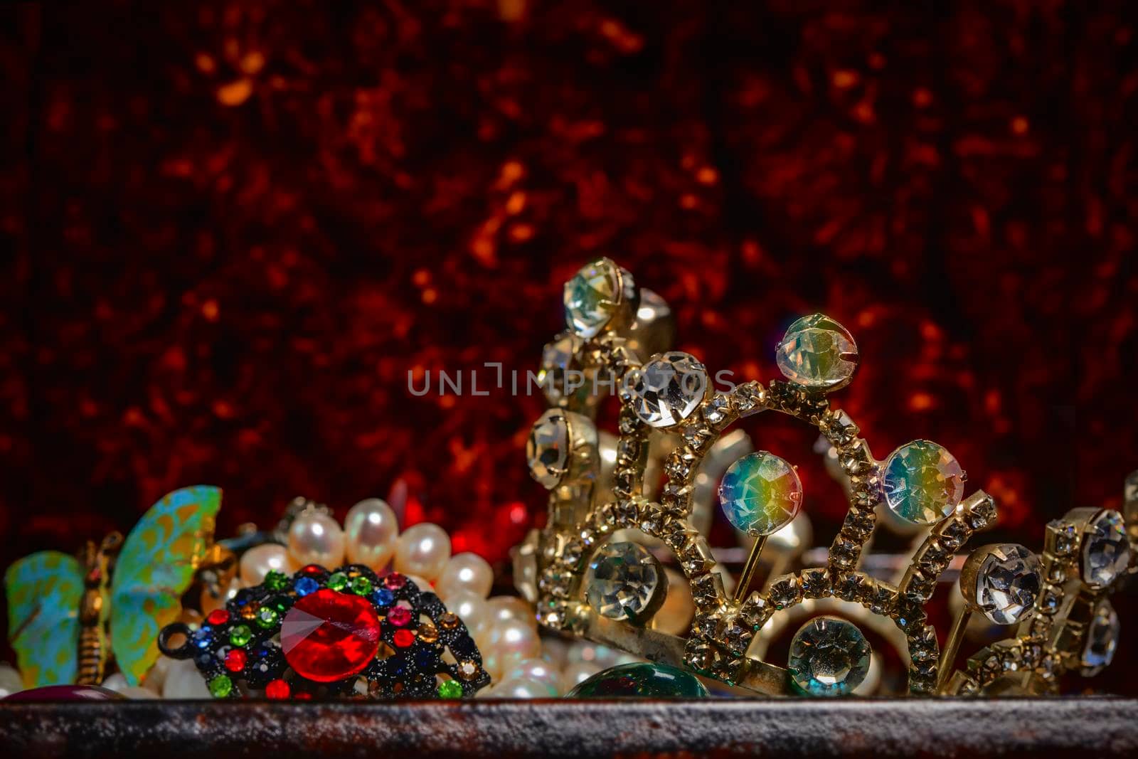 Part of bijouterie and crown on a red background.