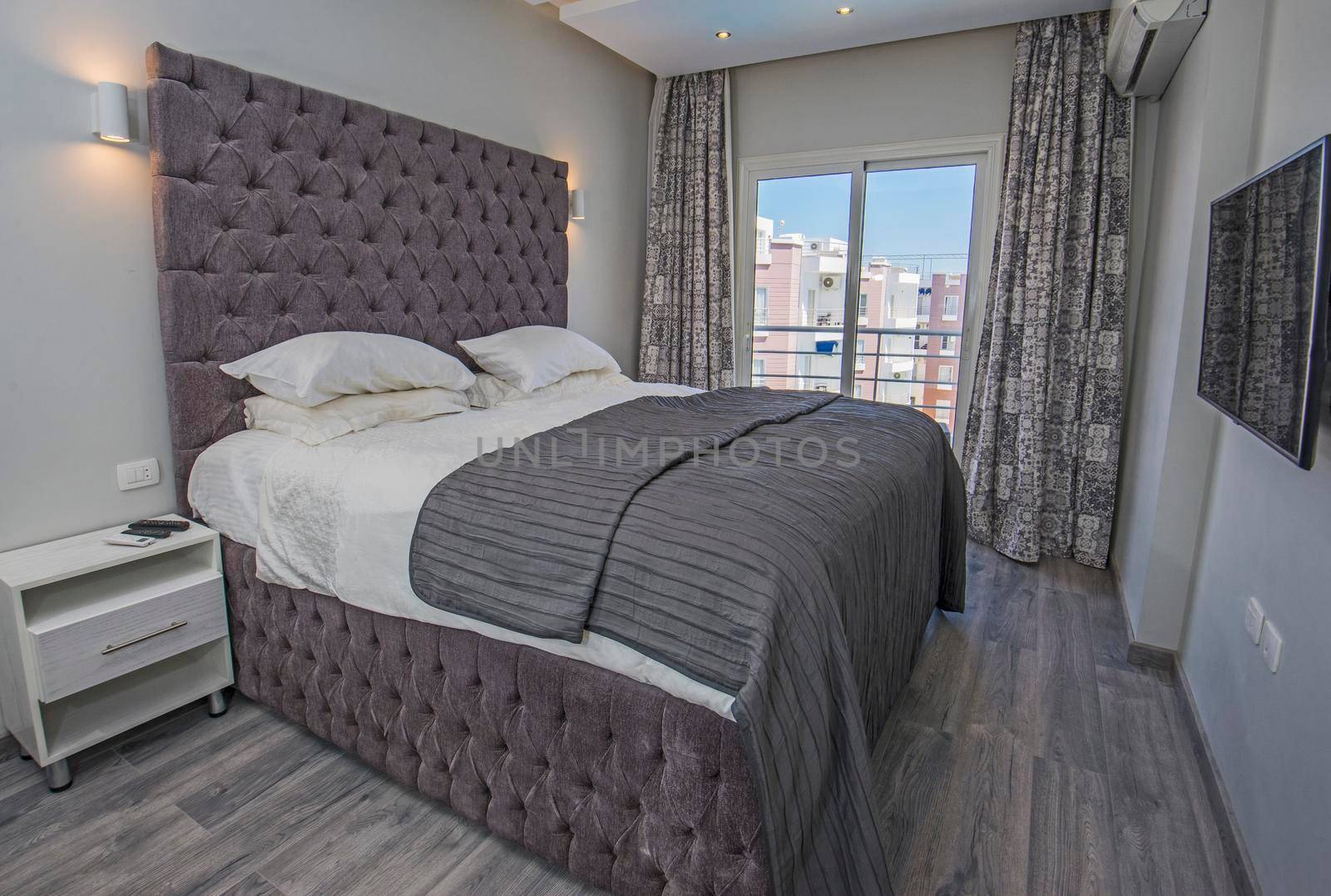 Interior design decor furnishing of luxury show home bedroom showing furniture and double bed in resort with outdoor balcony area