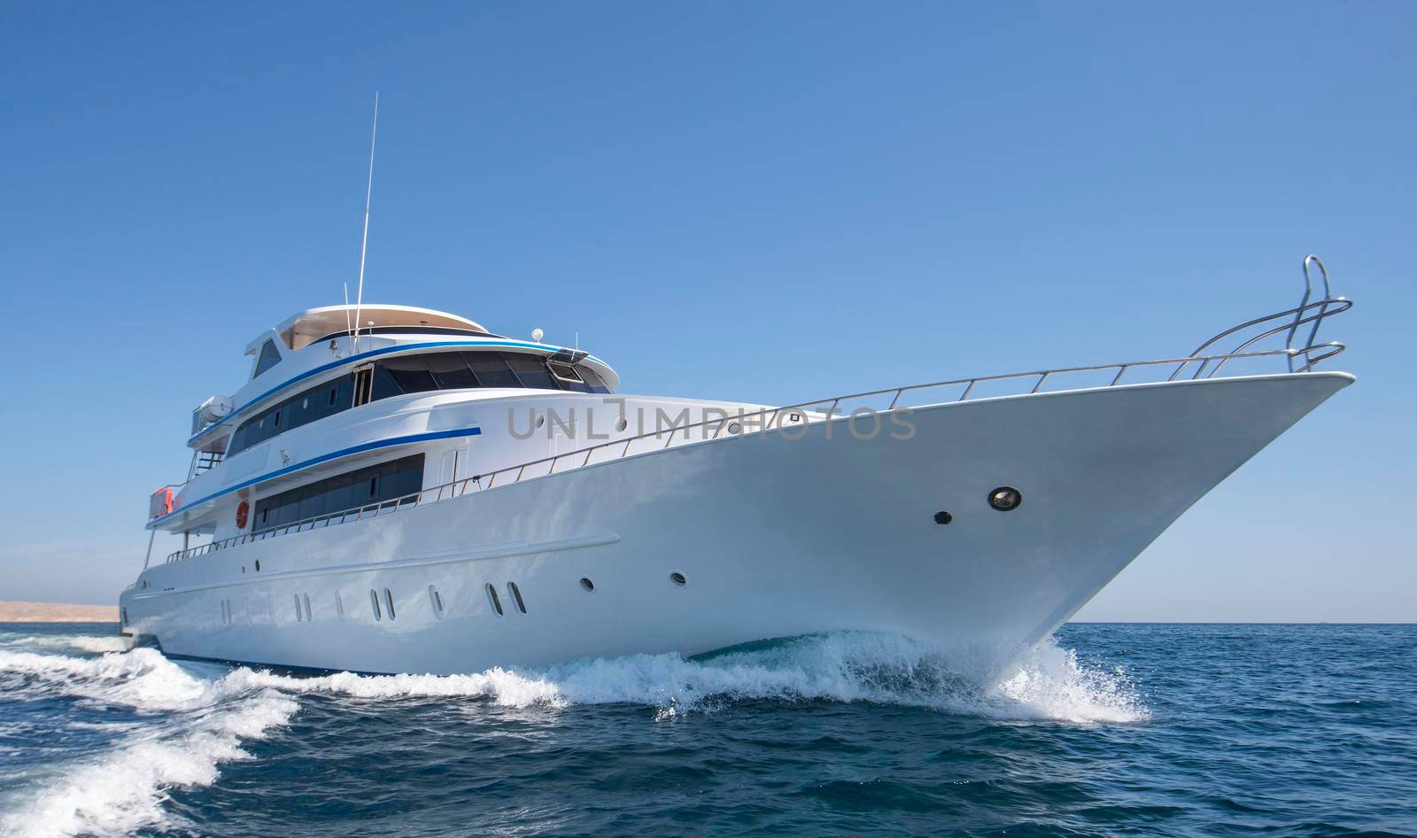 Luxury private motor yacht sailing under way on tropical sea with bow wave