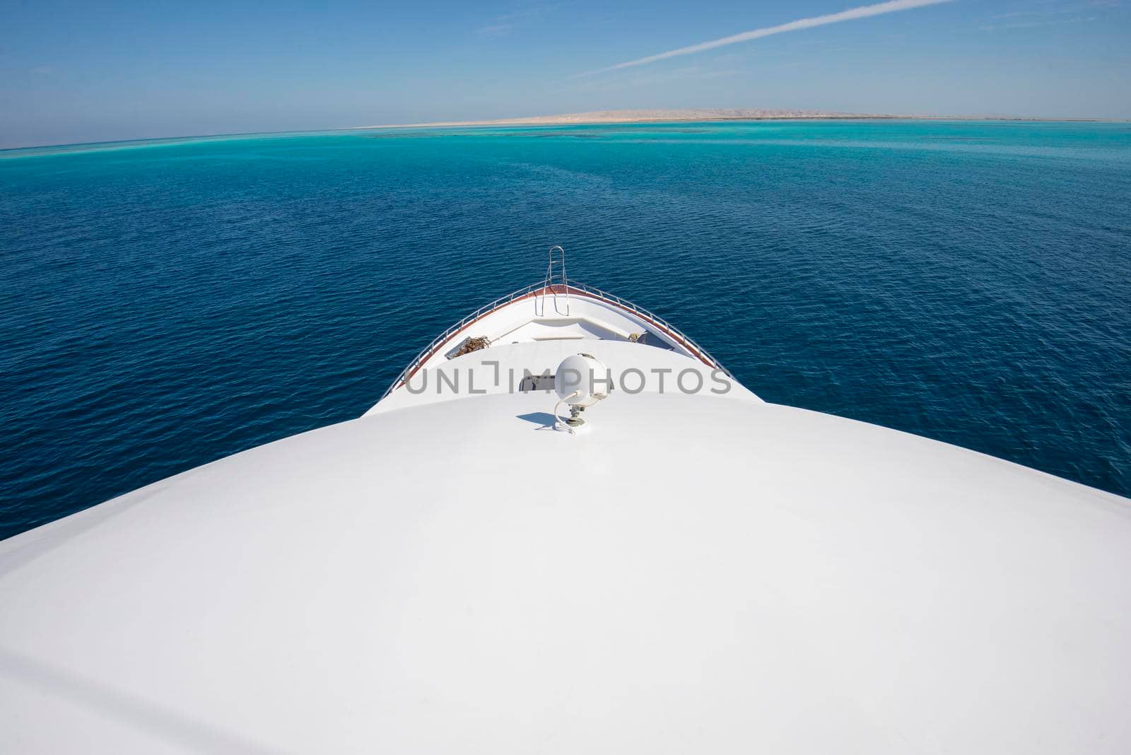 View over the bow deck of a large luxury motor yacht on the ocean with a tropical sea view background