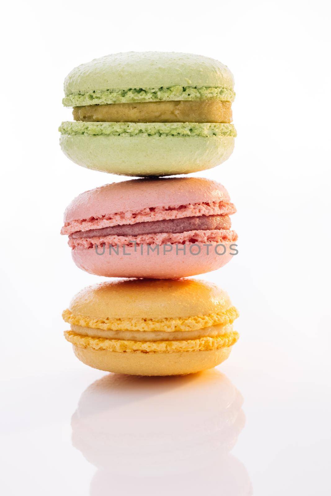 Vertical stack of three macarons against a bright white background. Sweet colorful macarons isolated on white background. Tasty colourful macaroons.