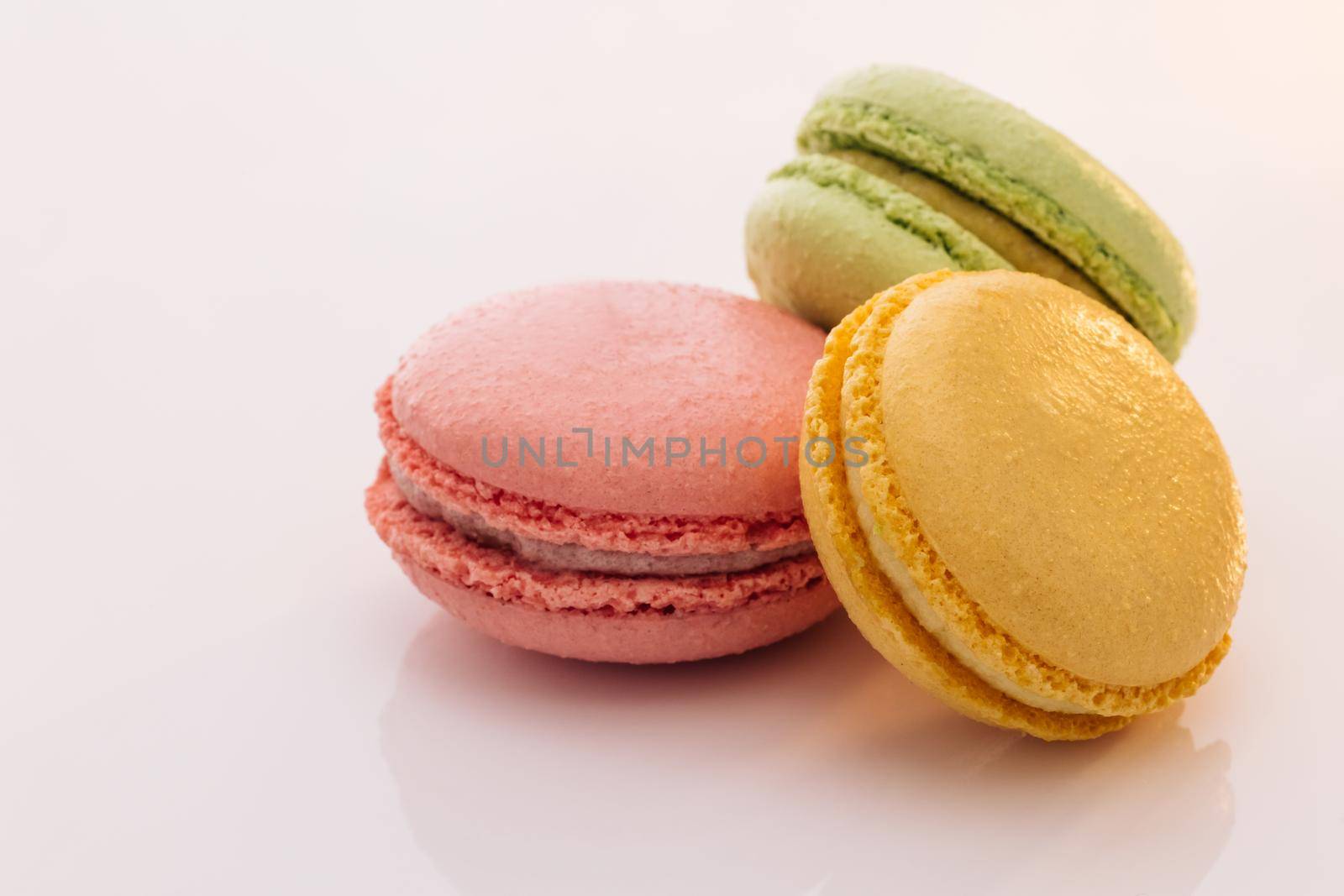 Three cookies macaroons are stacked on top of each other. Traditional French multicolored macaroon. Macaroons on white background. Food concept. by uflypro