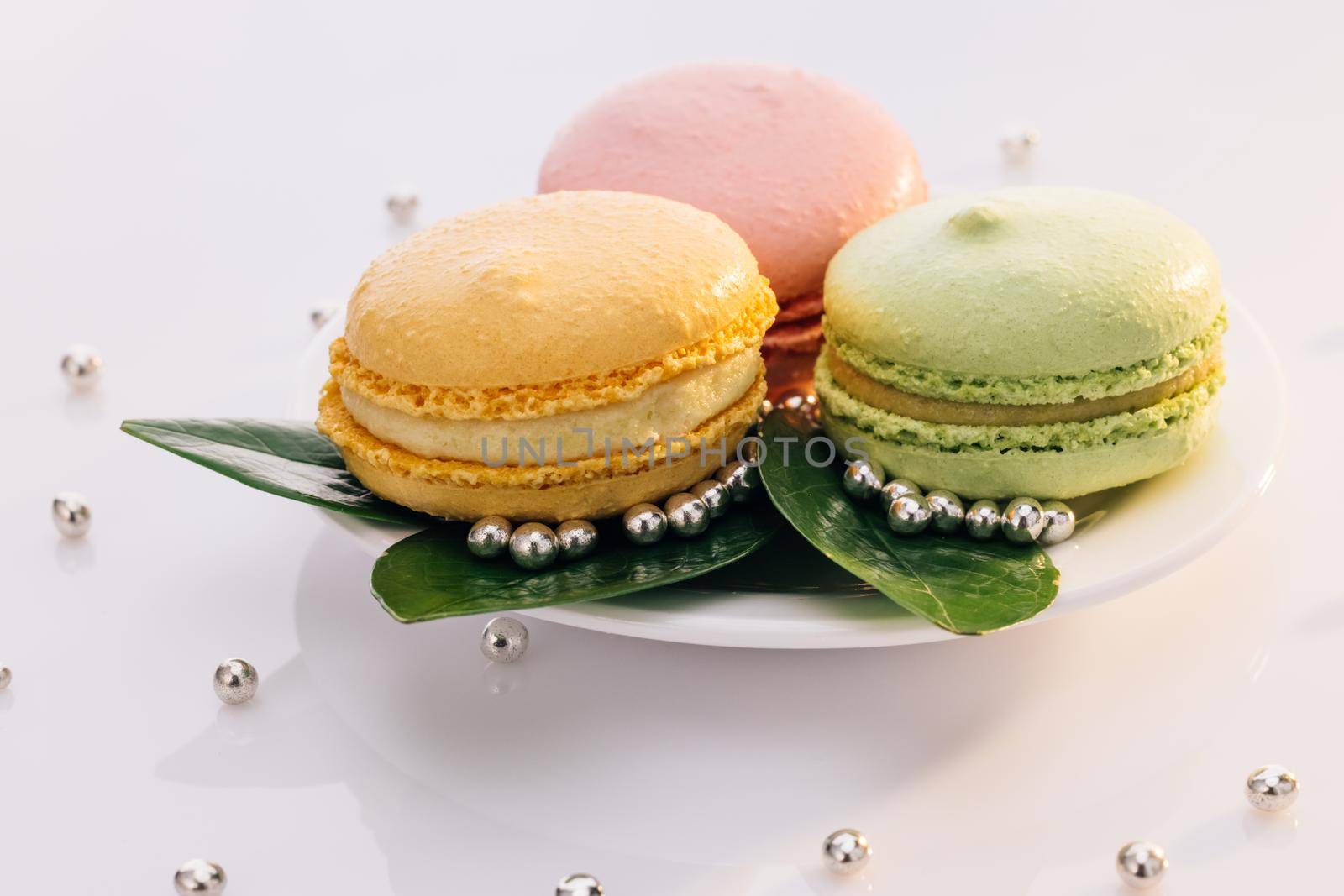 Close up of multicolor macarons , french macaroon, greedy pastry. French dessert sweets colored macaroons cookies arranged on a while plate on white background by uflypro