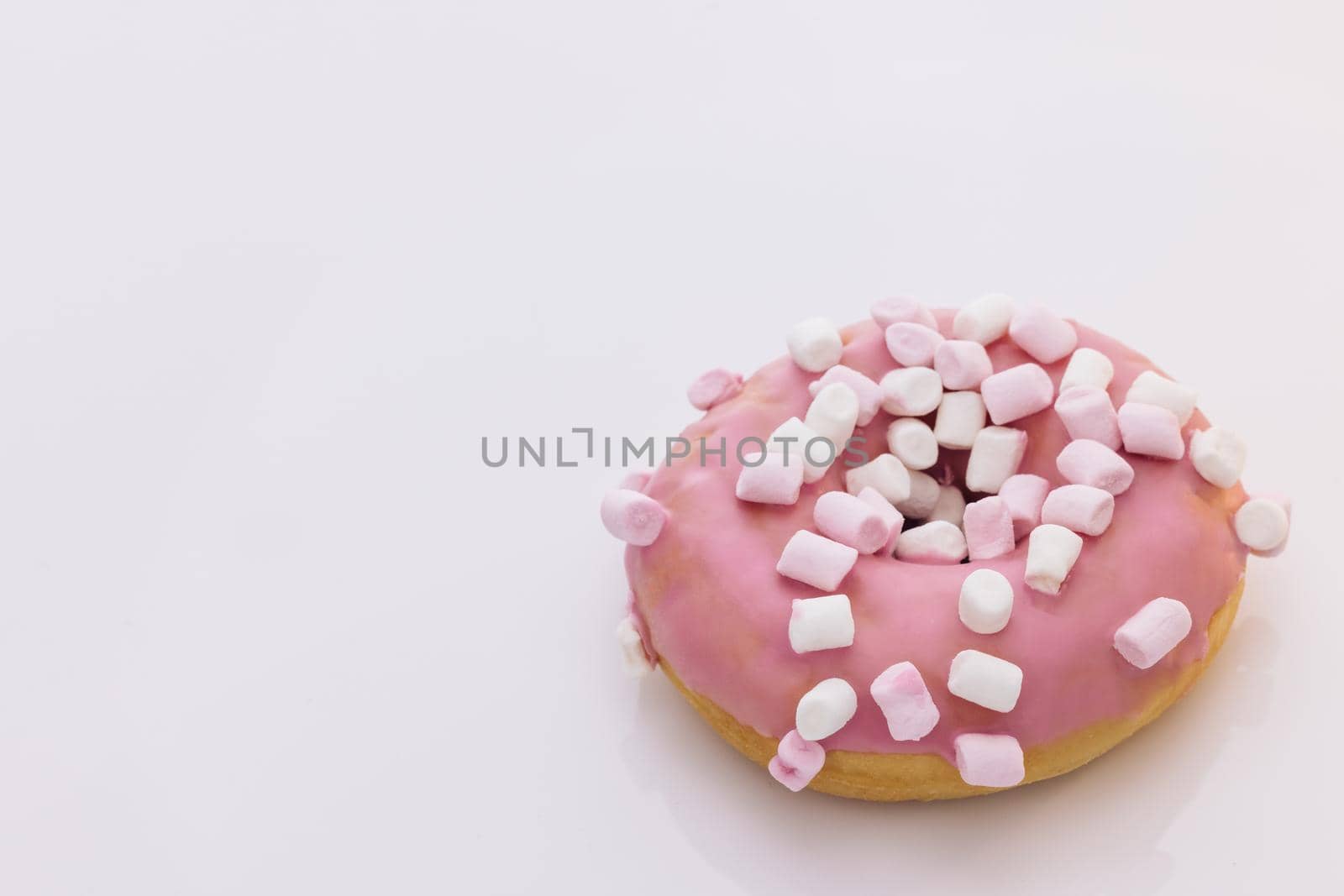 Bright and colorful sprinkled donut on a white background. Assortment of donuts of different flavors. Pink glazed marshmallow donut.