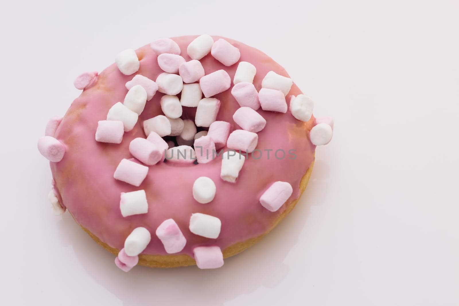 Close-up of pink donut on a white plate rotates. Sweet snacks baking. Sweet high-calorie food. Favorite donuts for kids. Donut cake for breakfast. Selective focus, shallow depth of field.