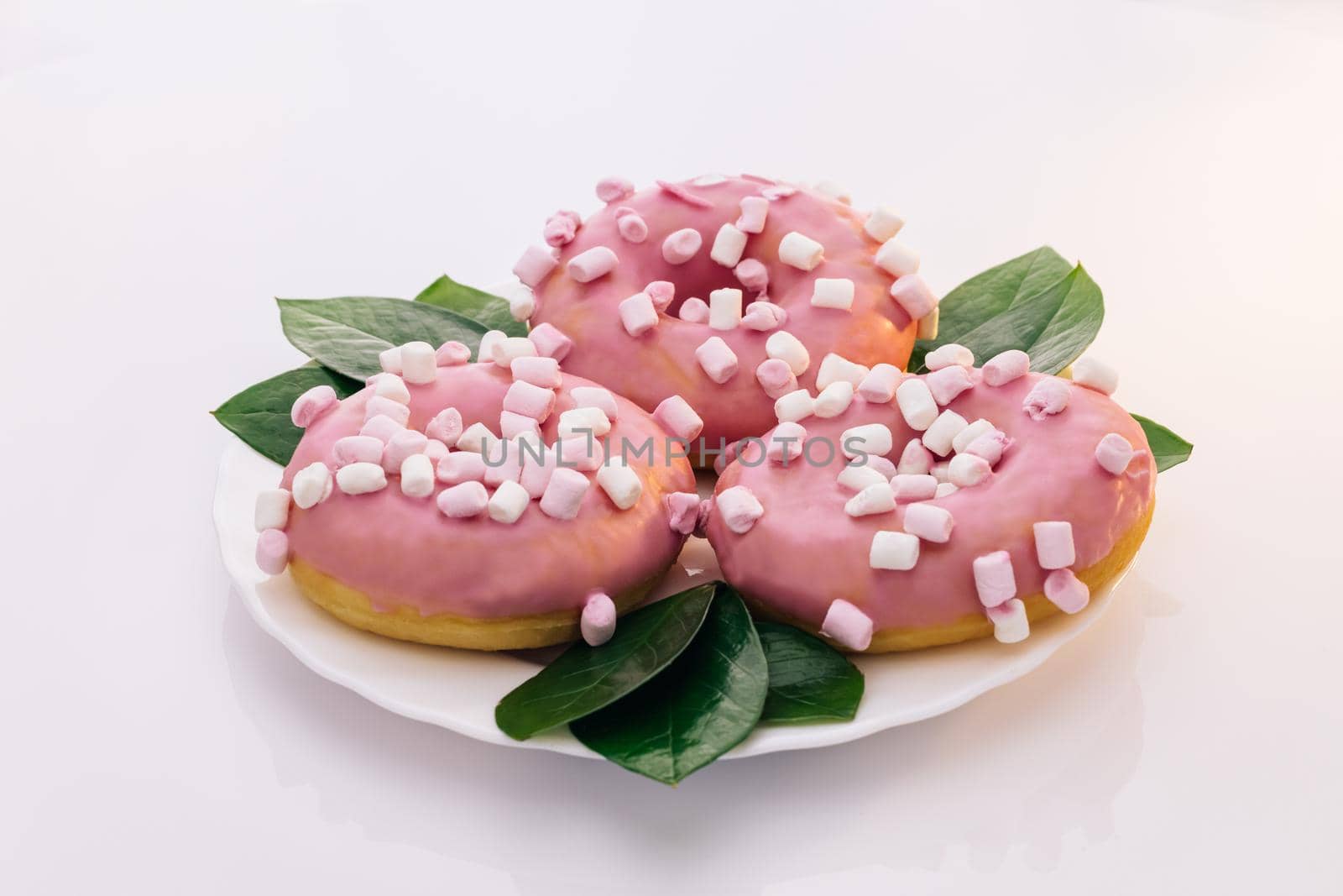 Colorful frosted pink doughnut. Assorted donuts. Pink glazed and sprinkles donuts. Rotating shot of white tasty delicious sweet donut with colorful sprinkles on white background. Dessert.