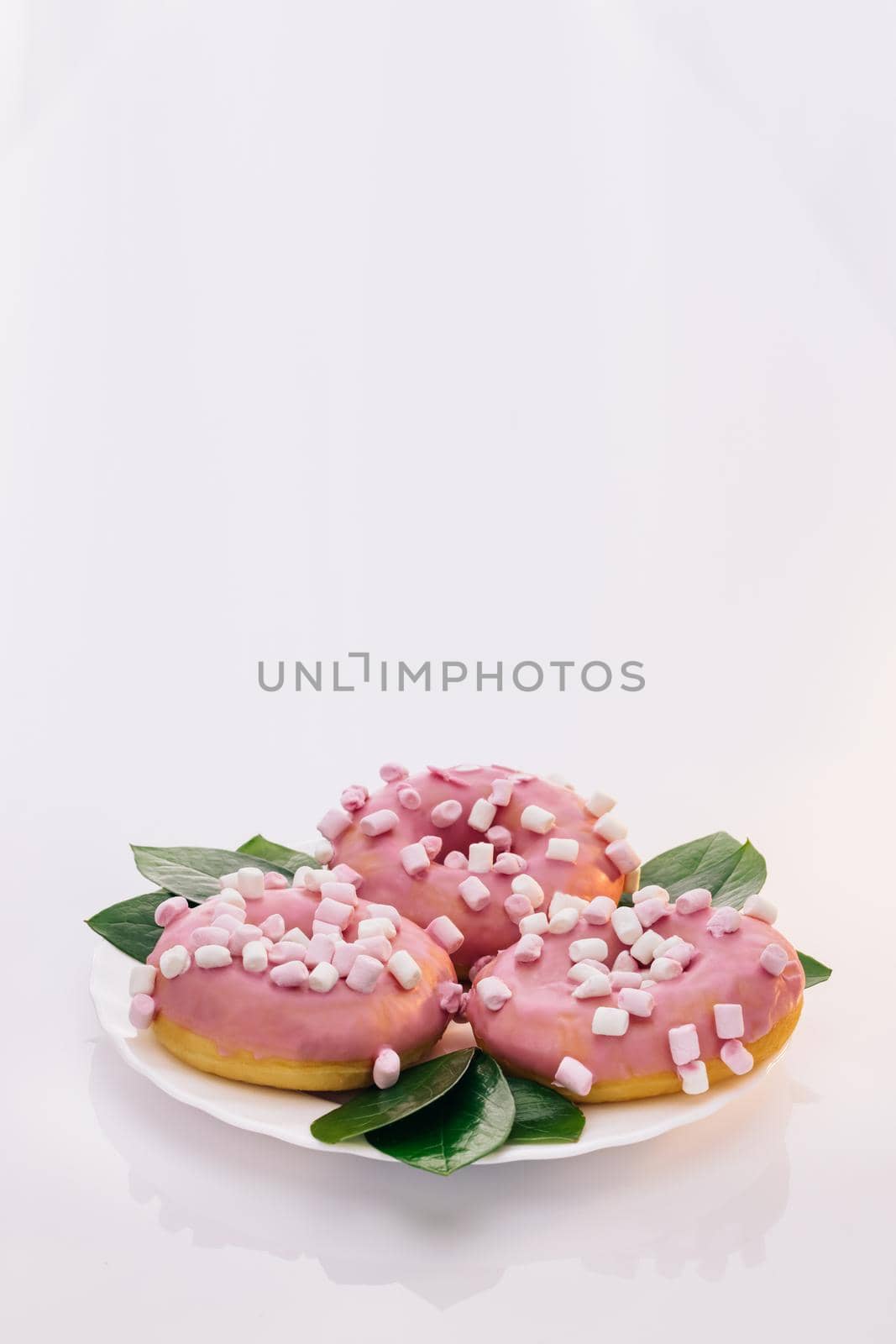 Pink glazed and sprinkles donuts. White tasty delicious sweet donut with colorful sprinkles on white background. Dessert. Colorful frosted pink doughnut. Assorted donuts by uflypro