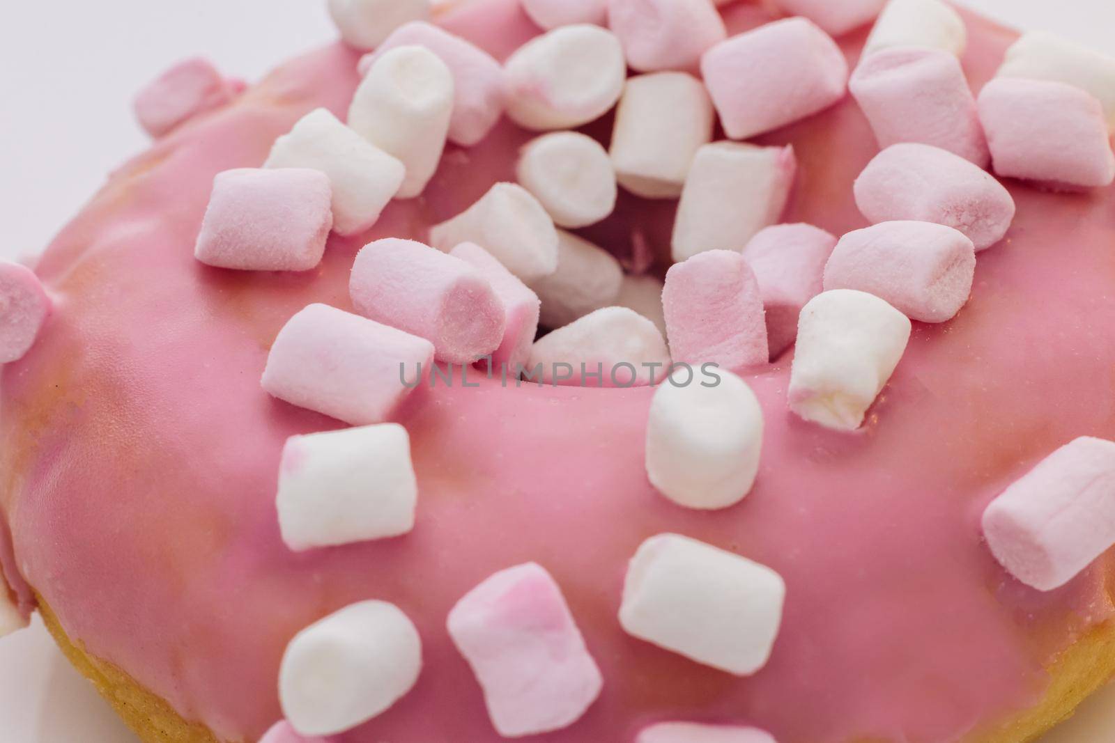 Close-up shot of pink tasty delicious sweet donut with colorful sprinkles on purple background. Dessert. Colorful frosted pink doughnut. by uflypro