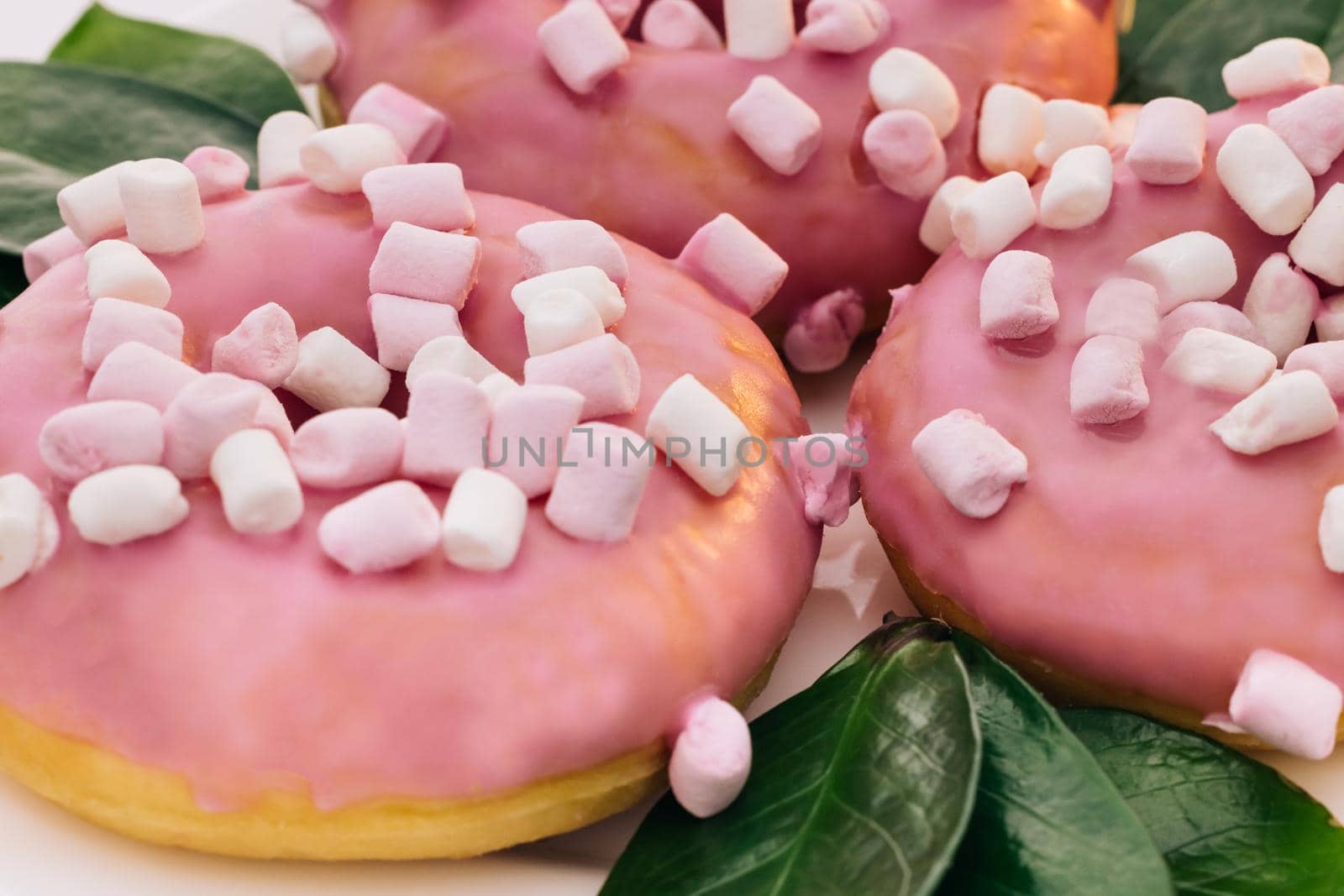 Close-up of a delicious round donuts covered with sweet icing rotates on a bright background. Sweet dessert pink donuts by uflypro