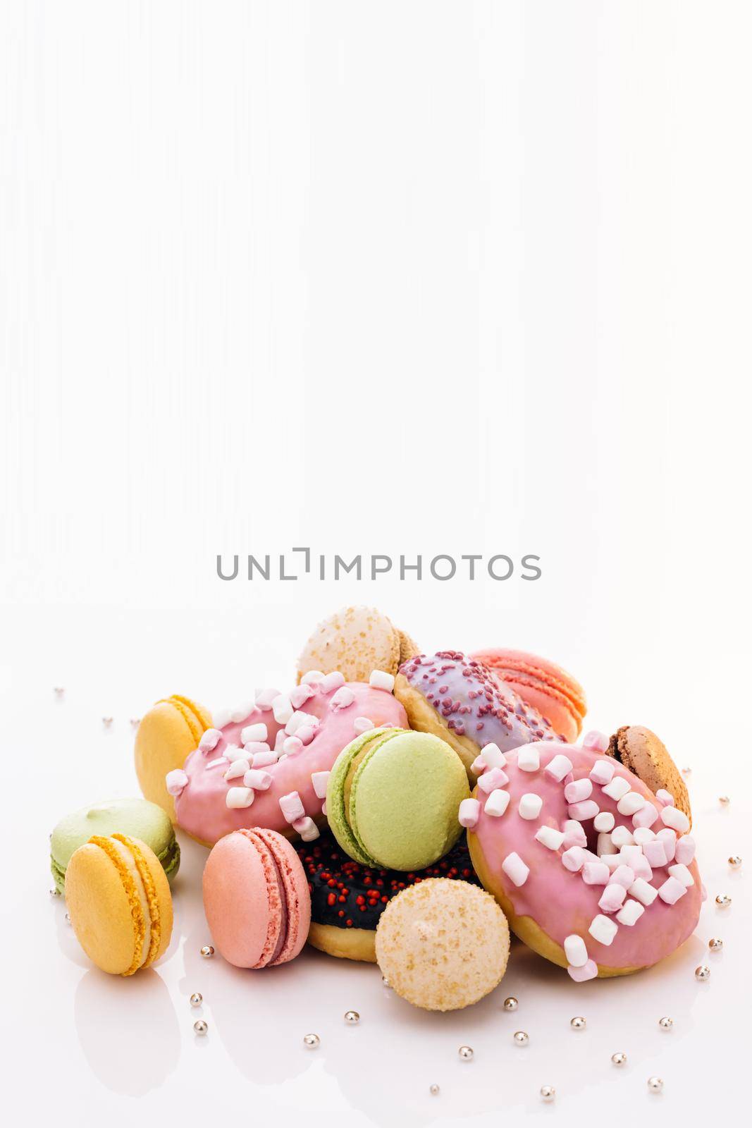 Many multi-colored macarons donuts with different tastes, dessert. Macaroons and donuts on a white background. French macaroons.