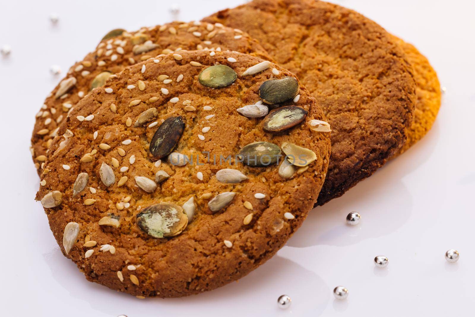 Oatmeal cookie on the table with sesame seeds on white background. Wheat fall on dietary cookies. Eat oatmeal cookies. The concept of making chip cookies by uflypro